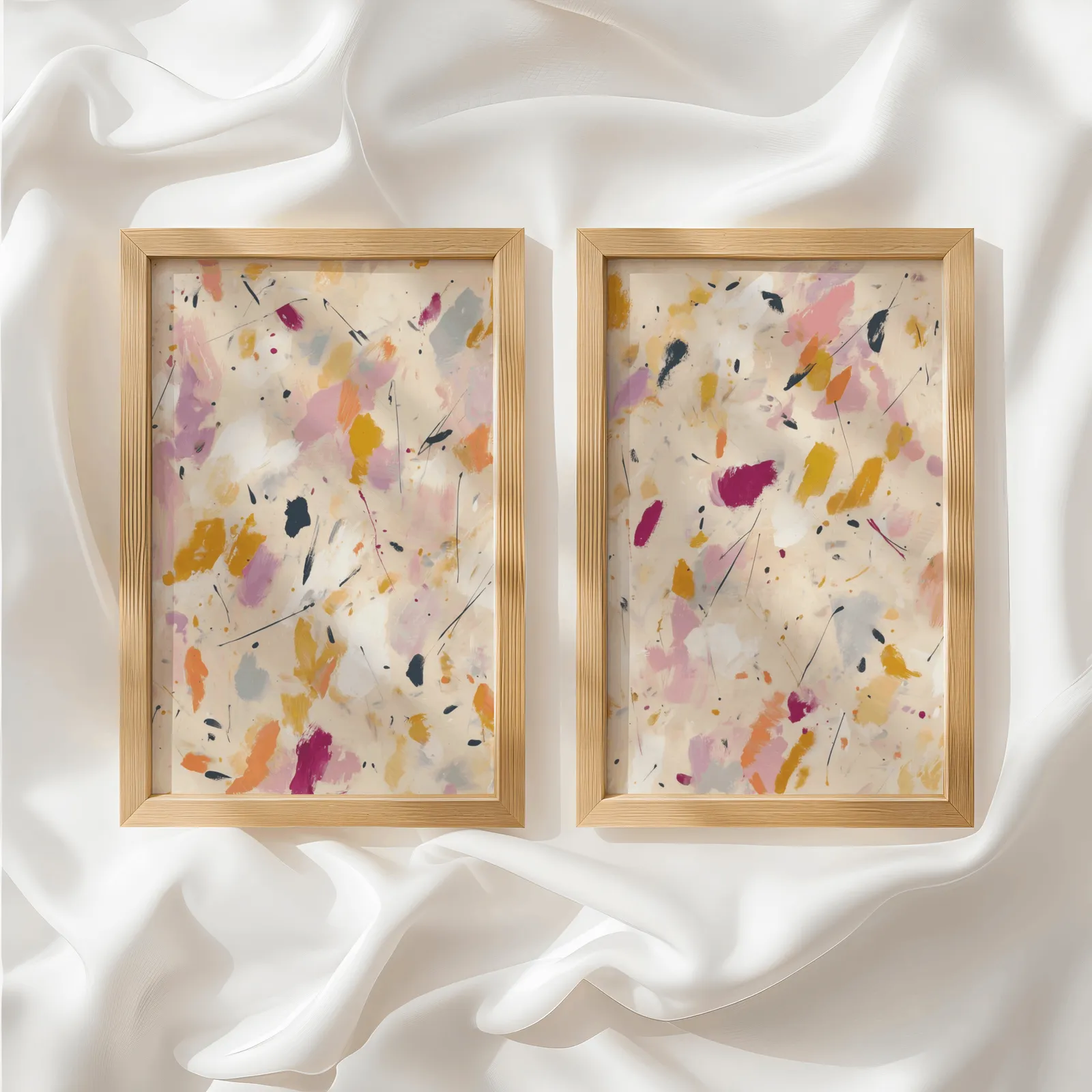 colorful abstract confetti wall art set of two, side by side atop rumpled white silky fabric