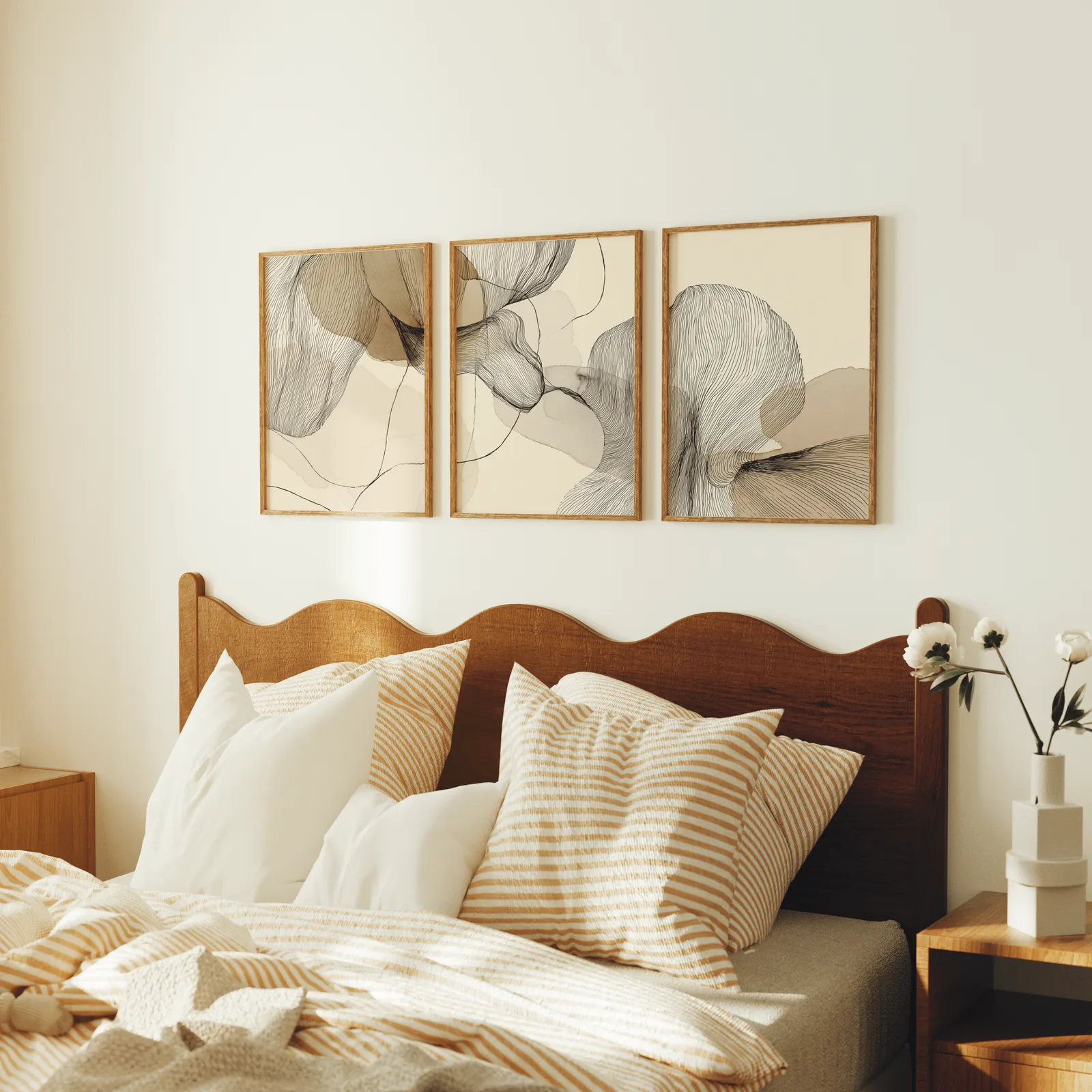 neutral abstract line art set of three, above a scalloped wooden headboard with striped pillows