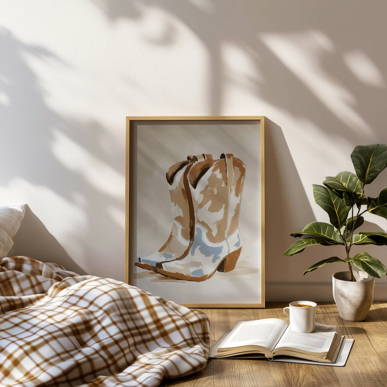 western cowgirl boots wall art in brown and beige, leaning on a sunlit floor beside a plaid blanket and open book
