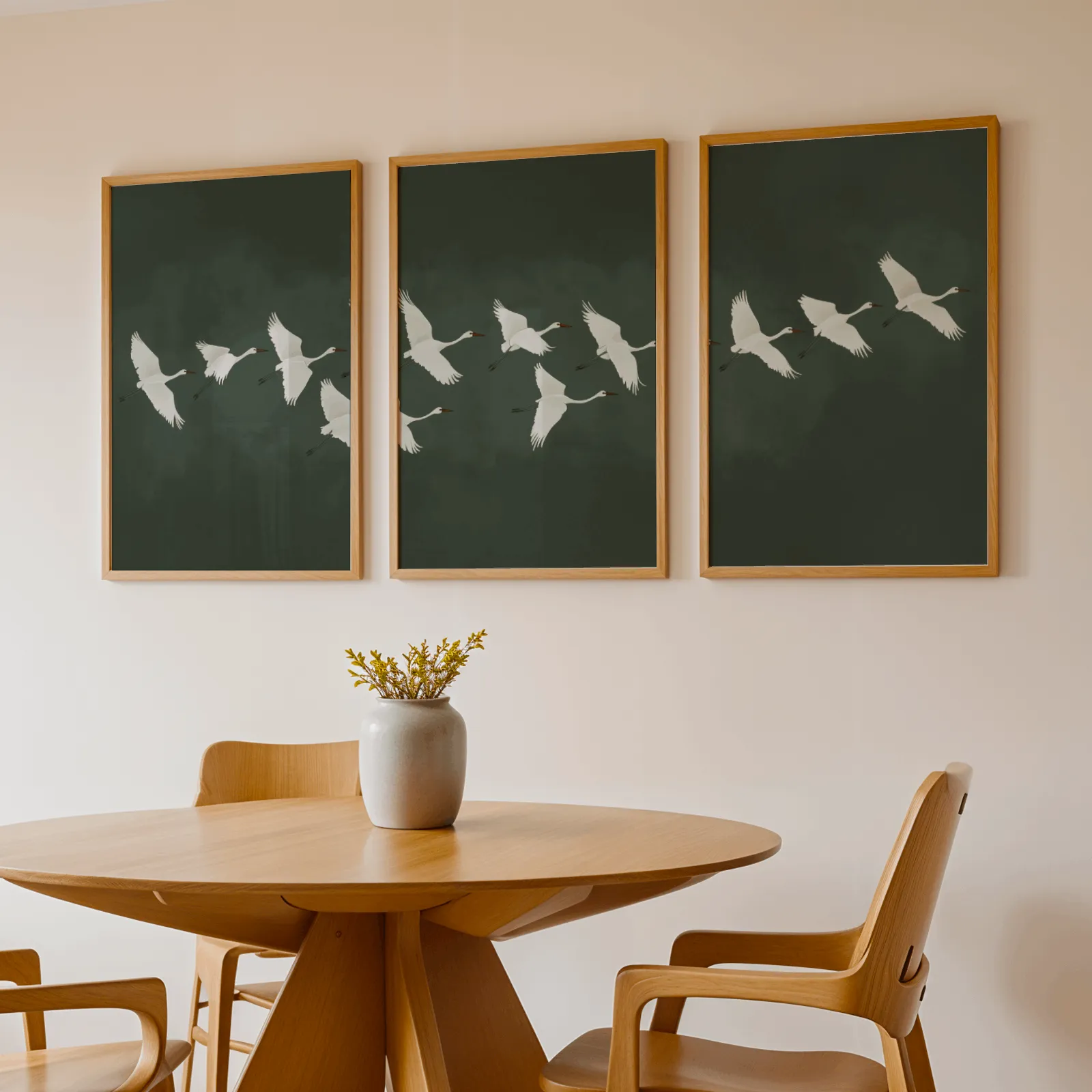 green crane wall art set of 3, above a round wooden table with a stoneware vase