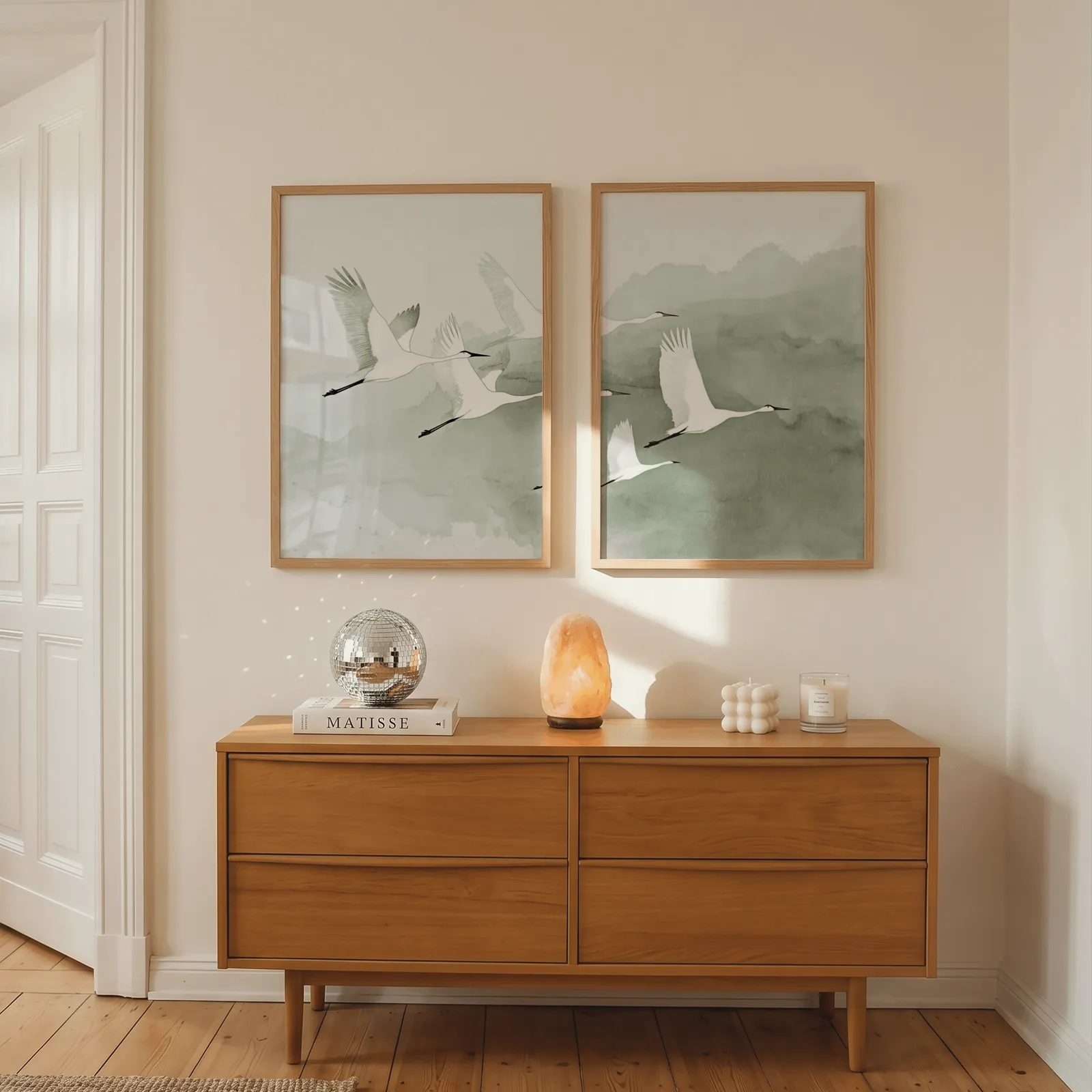 green crane wall art set of two prints, above a wooden dresser with a salt lamp and disco ball