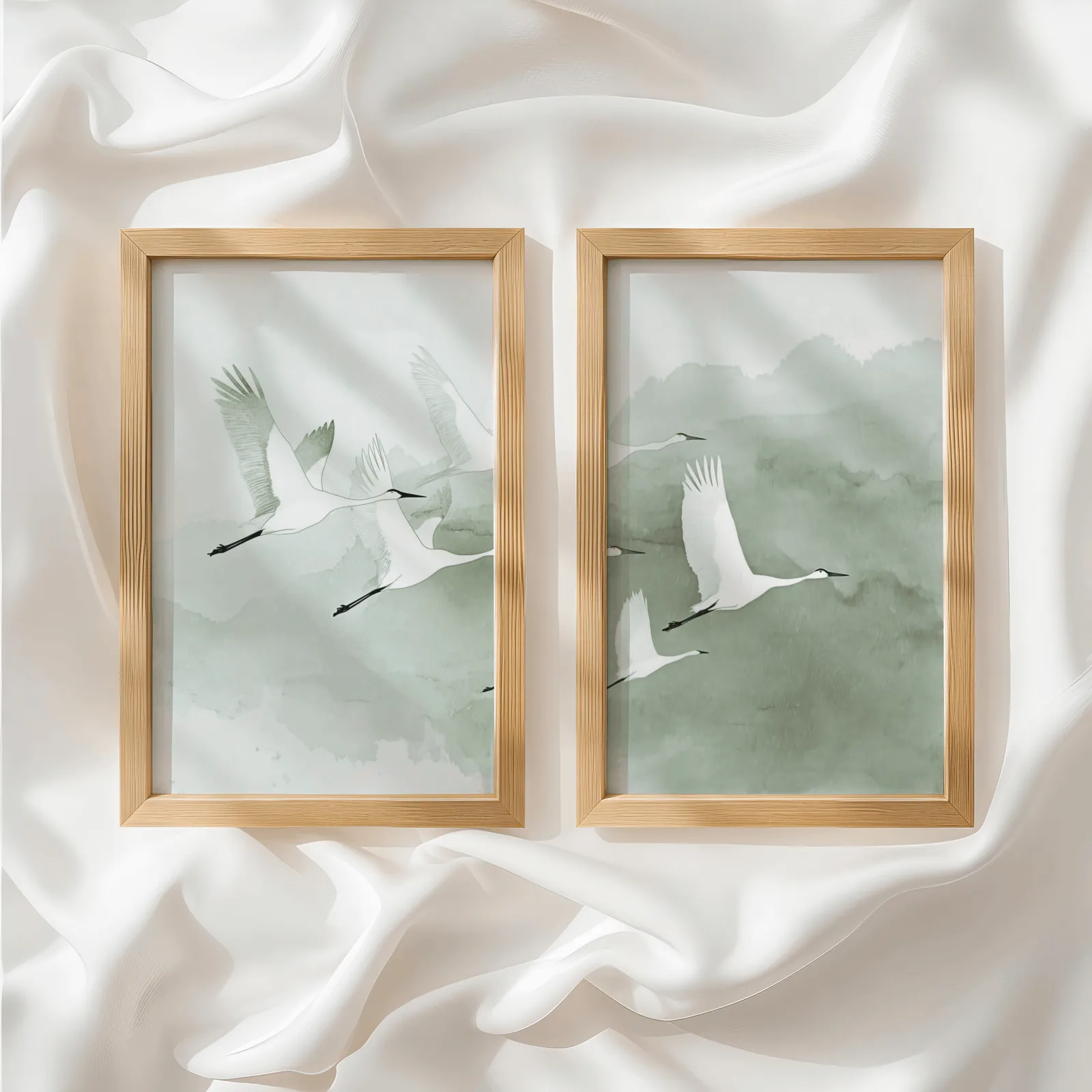 green crane wall art set of two prints, side by side atop rumpled white silky fabric