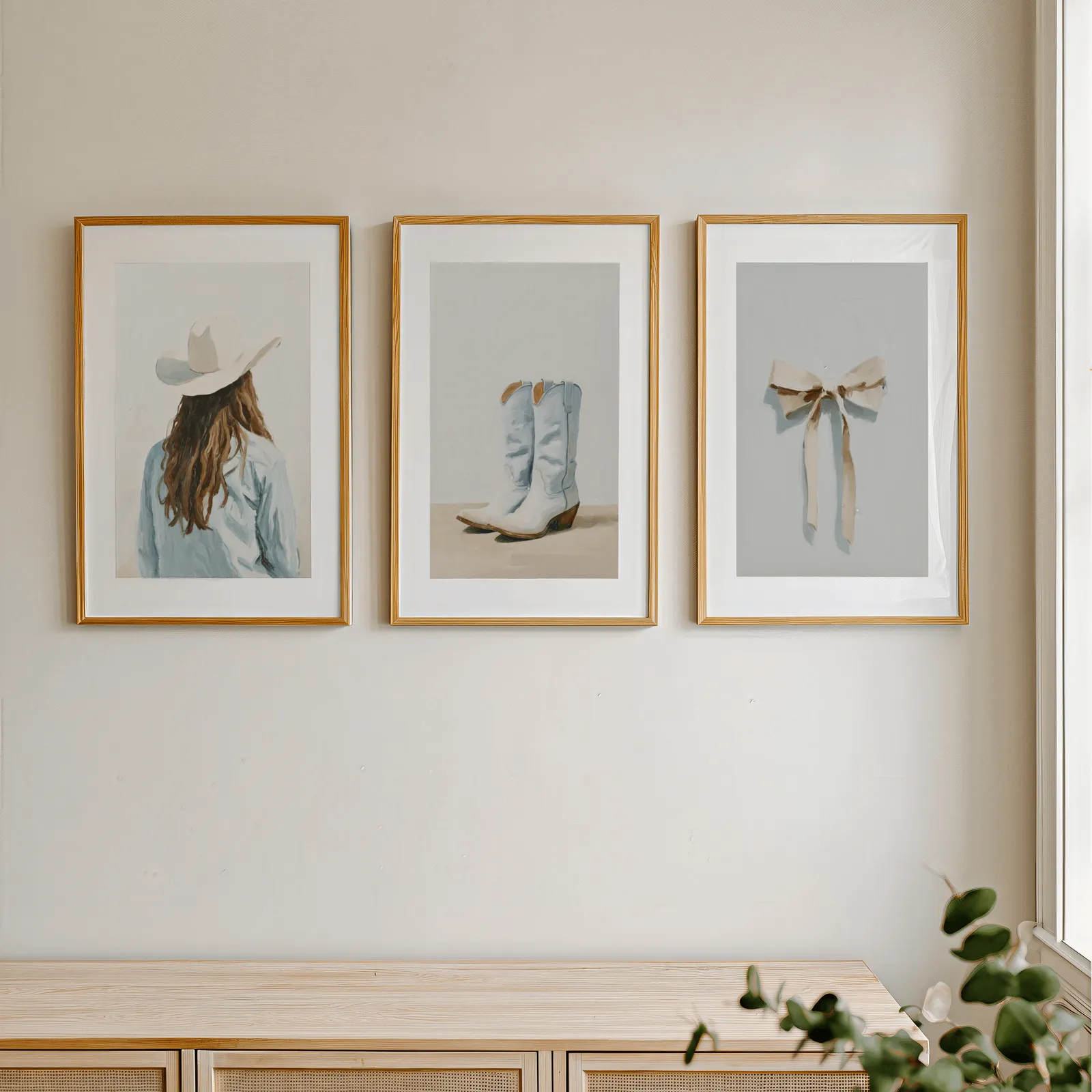 western cowgirl wall art set with boots and bow, in a row above a light wooden sideboard near a window
