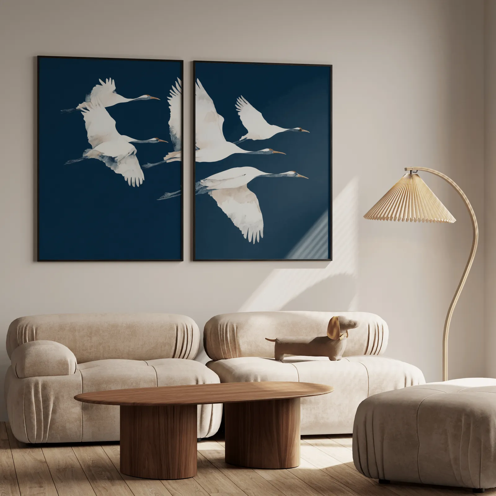 blue crane wall art set of two prints, above a plush beige sofa with a pleated lamp nearby