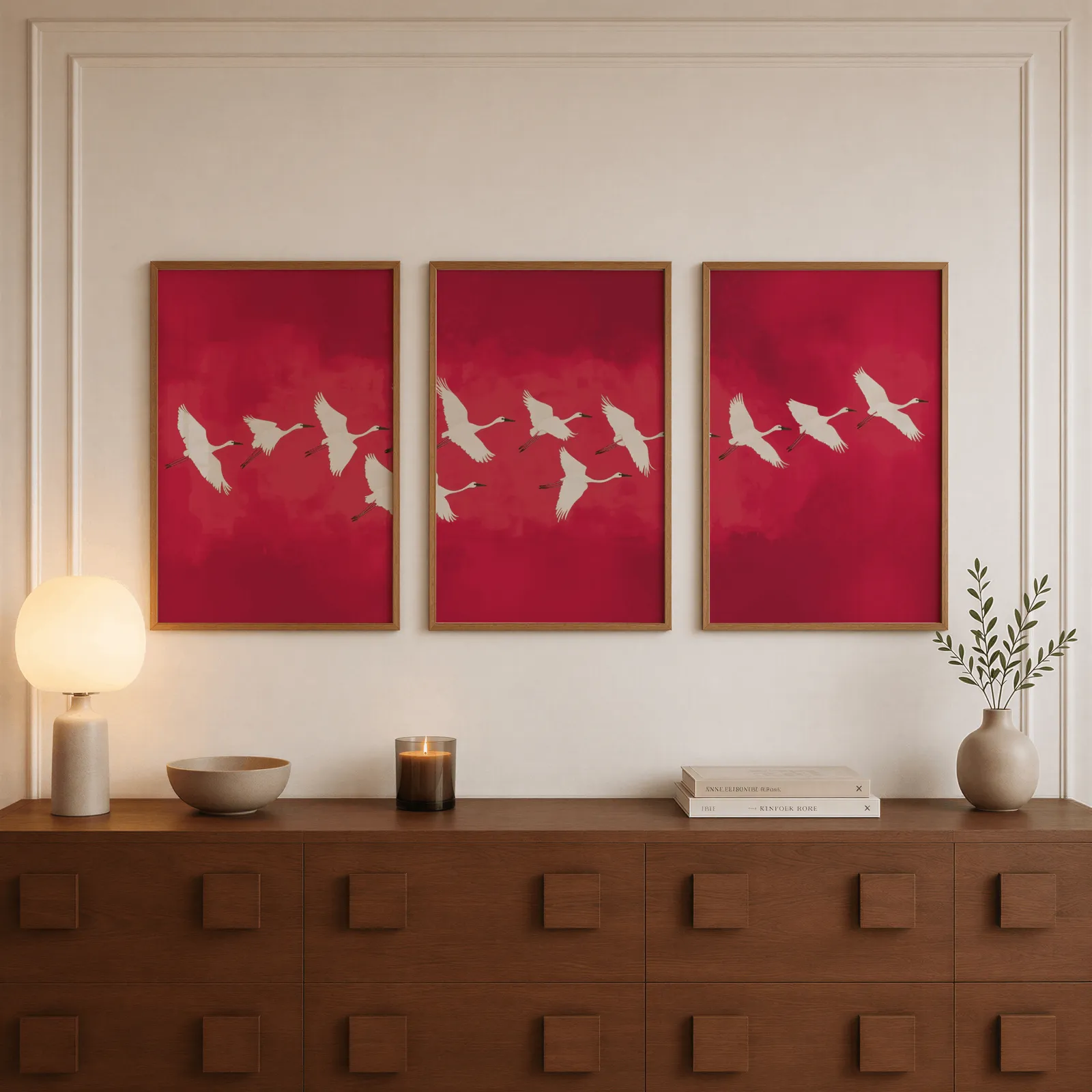 red crane wall art triptych, above a walnut sideboard with a lit candle and glowing lamp