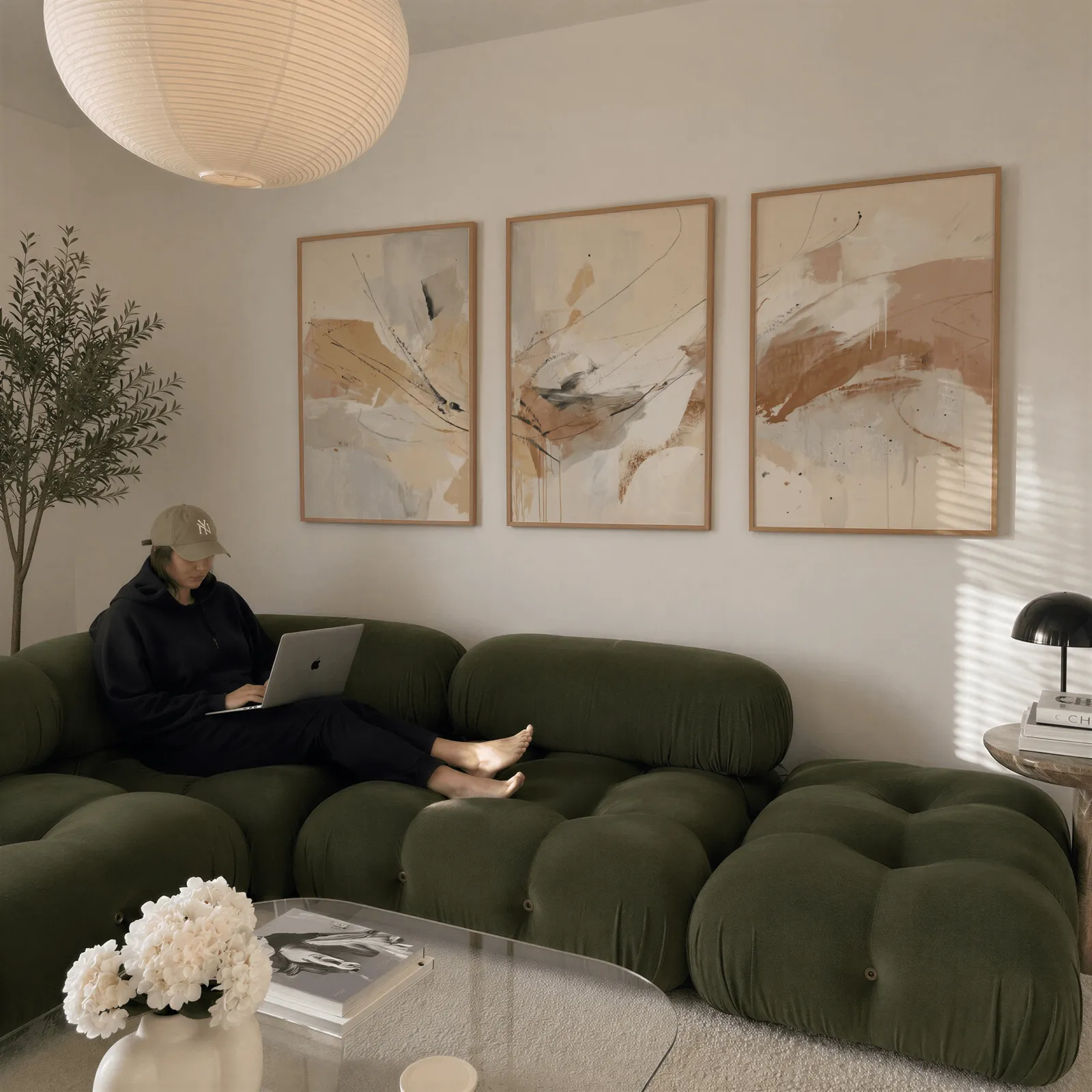 neutral abstract wall art set of 3, above a plush olive velvet sectional beneath a paper lantern light