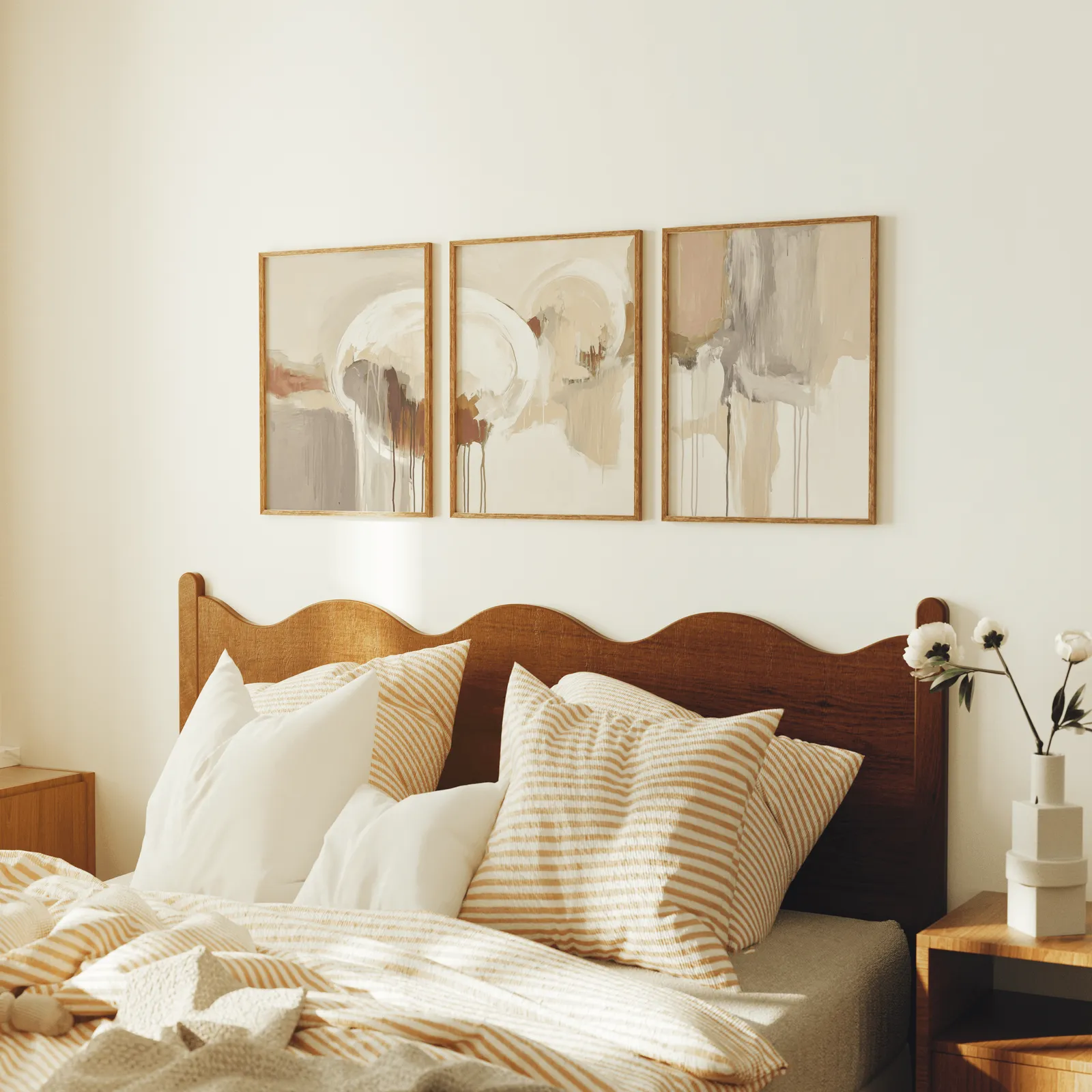 terracotta and grey abstract wall art set of 3, above a scalloped wooden headboard with striped pillows
