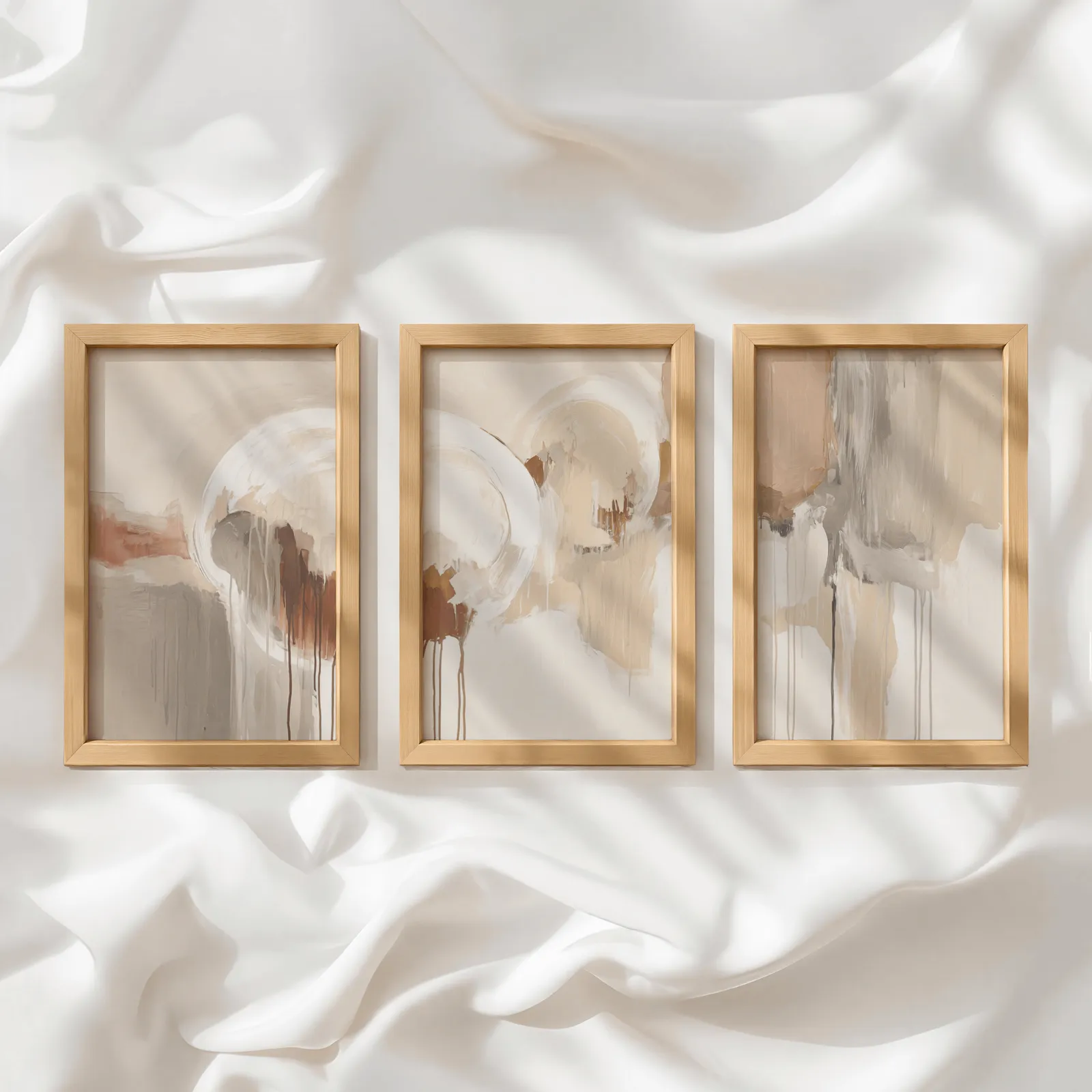 terracotta and grey abstract wall art set of 3, in a row atop rumpled white silky fabric