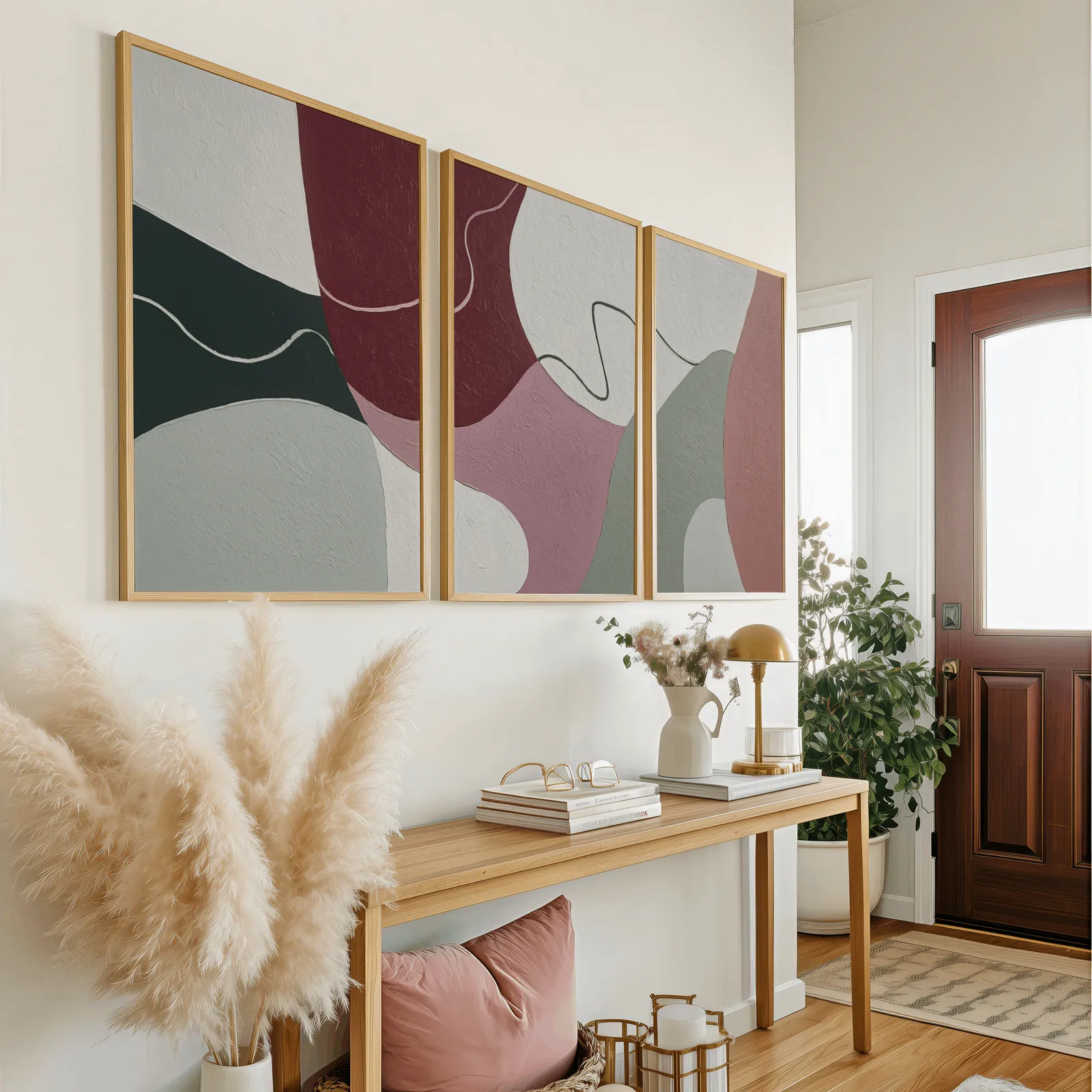 abstract triptych wall art in burgundy and pink, above a wooden console table near the entry door
