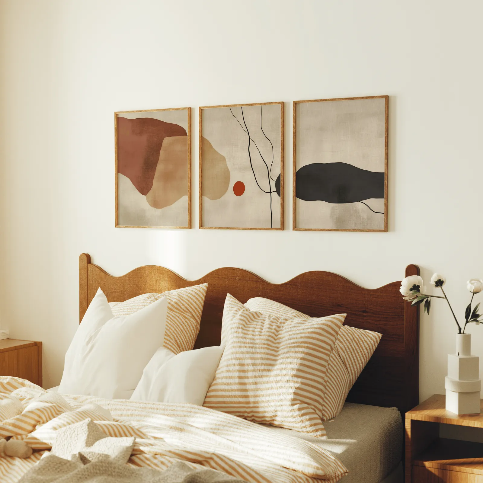 terracotta abstract minimalist wall art set of 3, above a scalloped wooden headboard with striped pillows