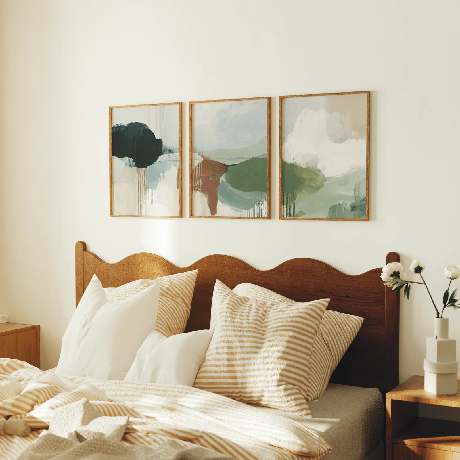 green terracotta abstract wall art set of 3, above a scalloped wooden headboard with striped pillows