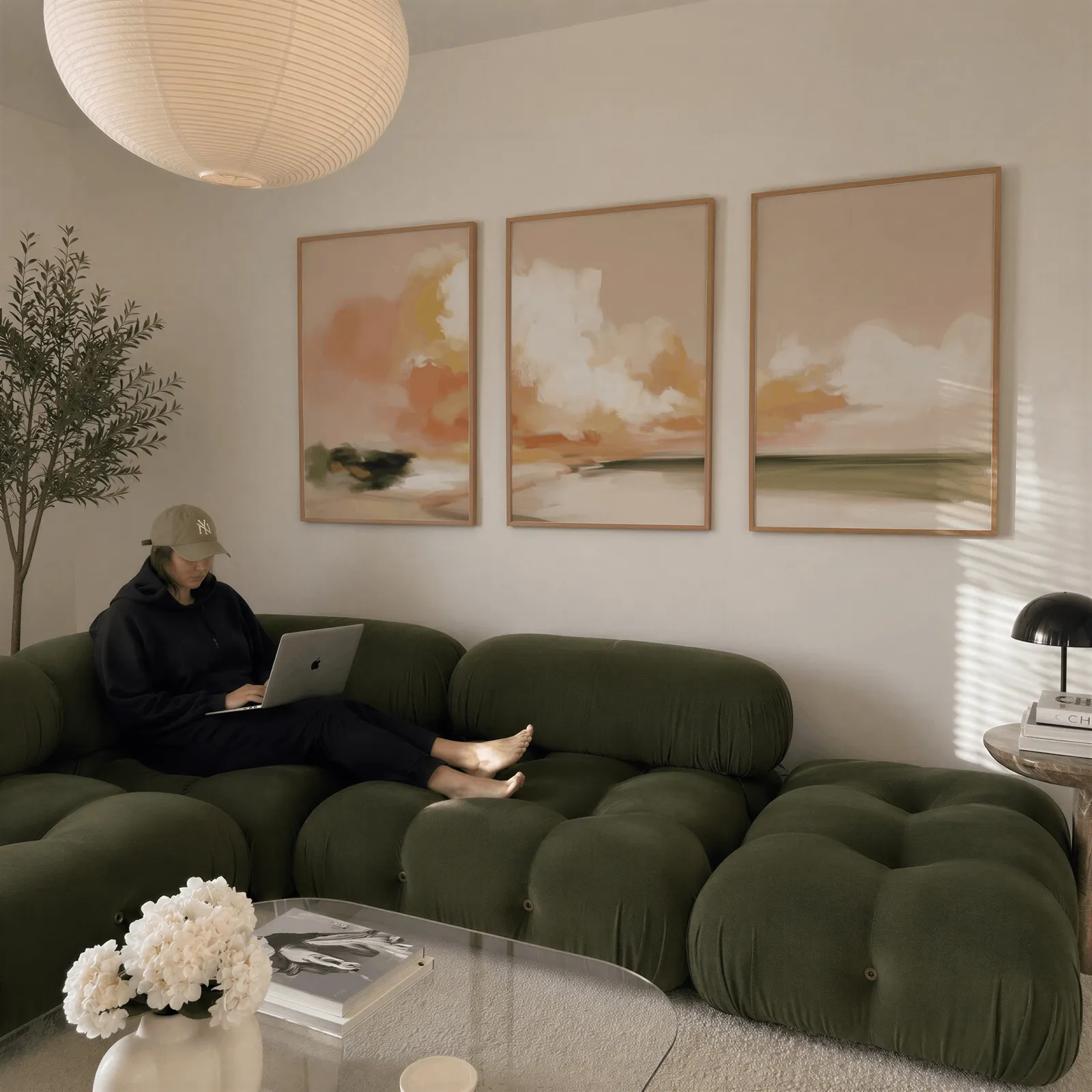 terracotta coastal landscape triptych wall art, above a plush olive velvet sectional beneath a paper lantern light