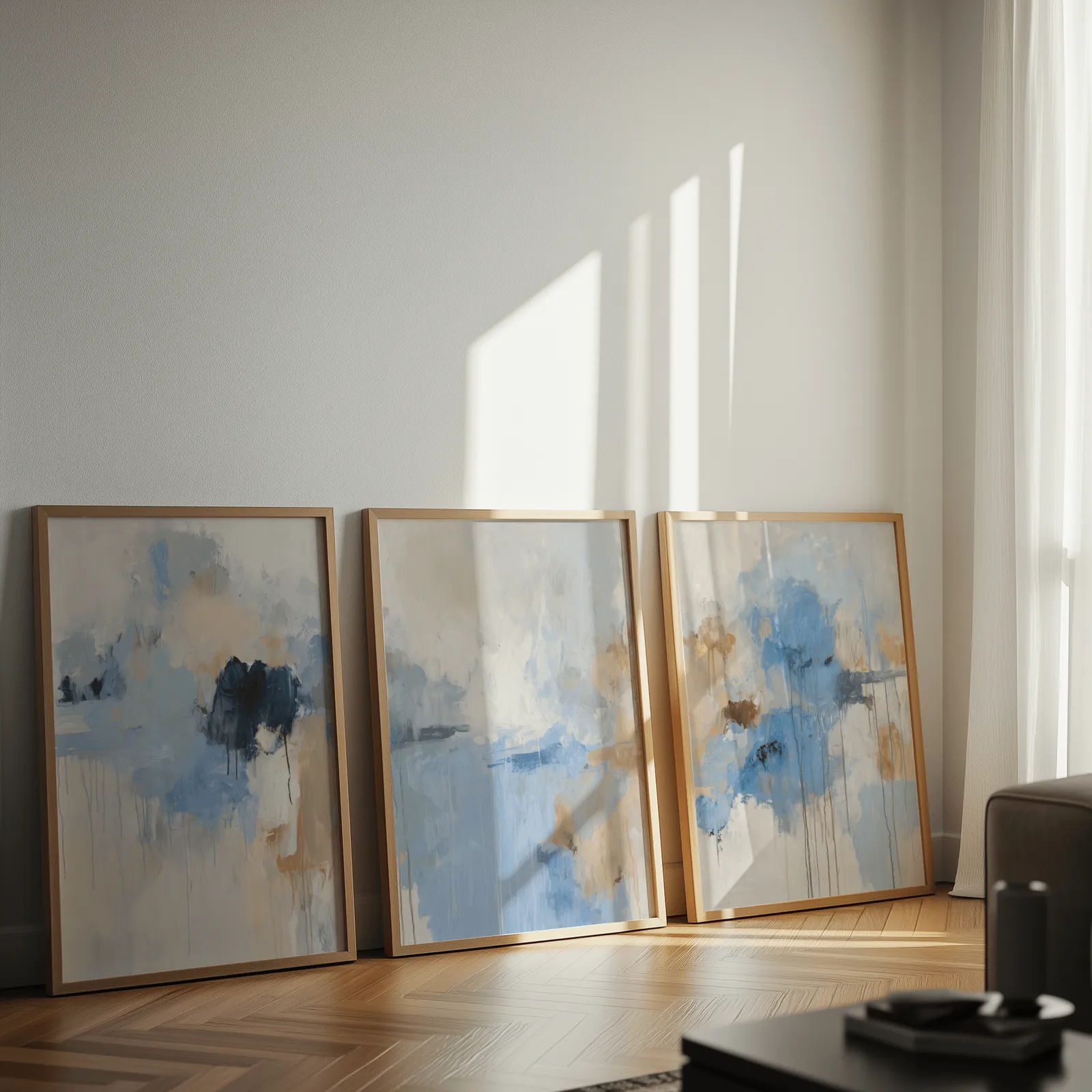 blue abstract three piece wall art, leaning against a sunlit wall on herringbone flooring