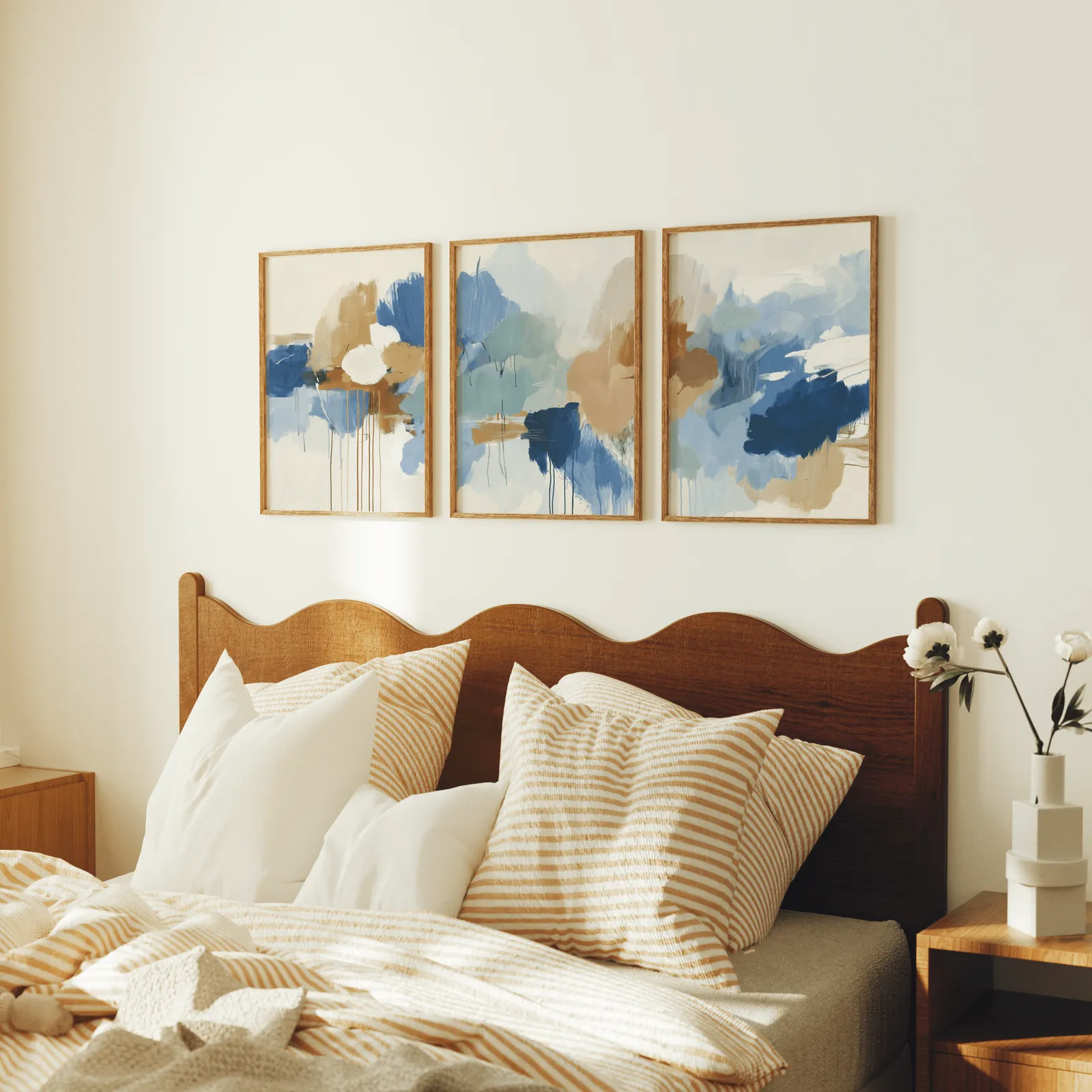 blue and terracotta abstract triptych wall art, above a scalloped wooden headboard with striped pillows