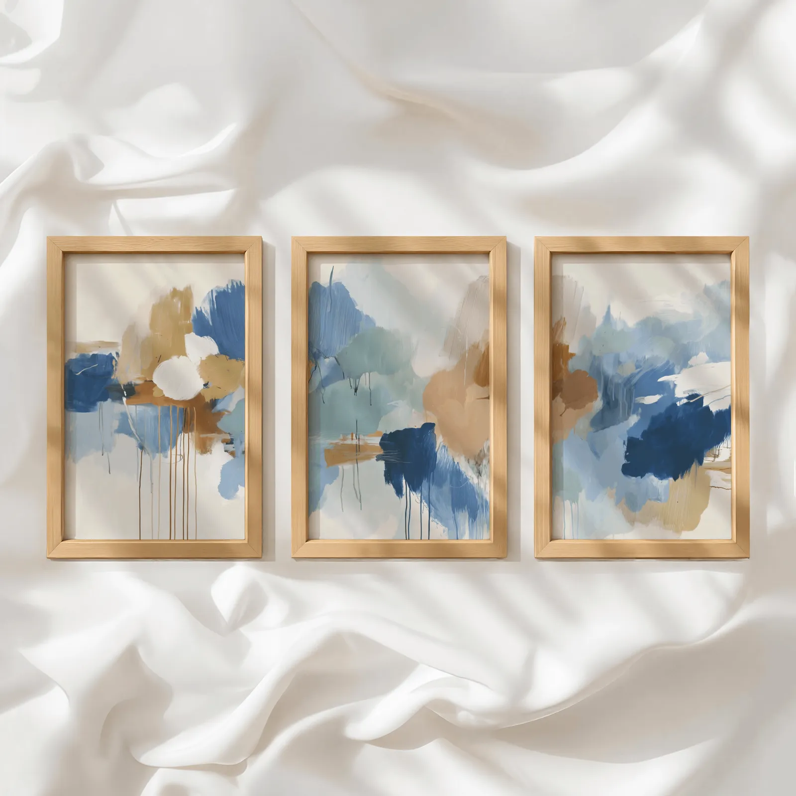 blue and terracotta abstract triptych wall art, in a row atop rumpled white silky fabric