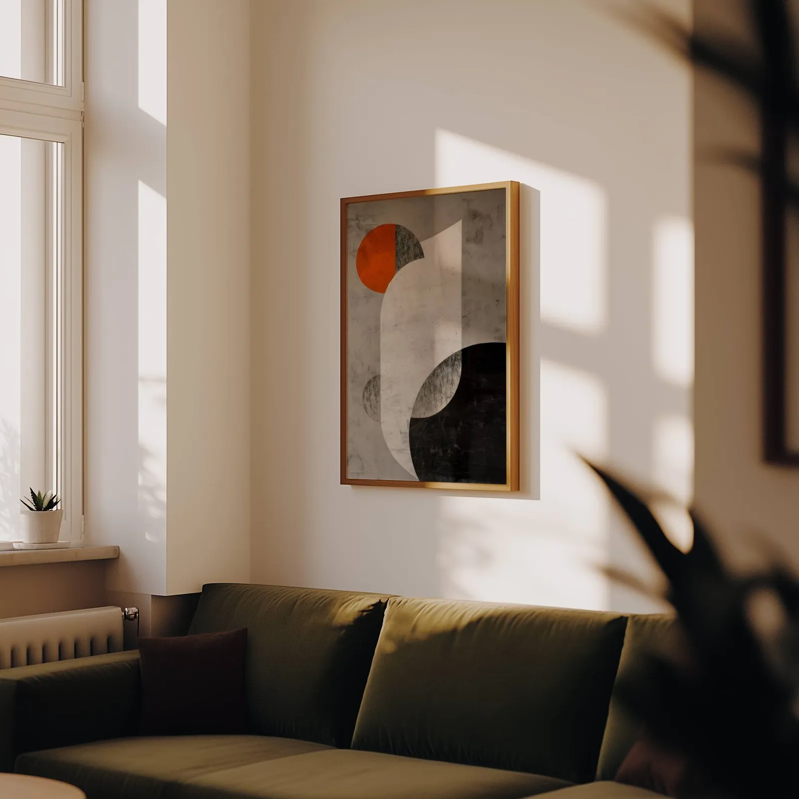 orange and black abstract geometric wall art, above an olive velvet sofa in raking afternoon light