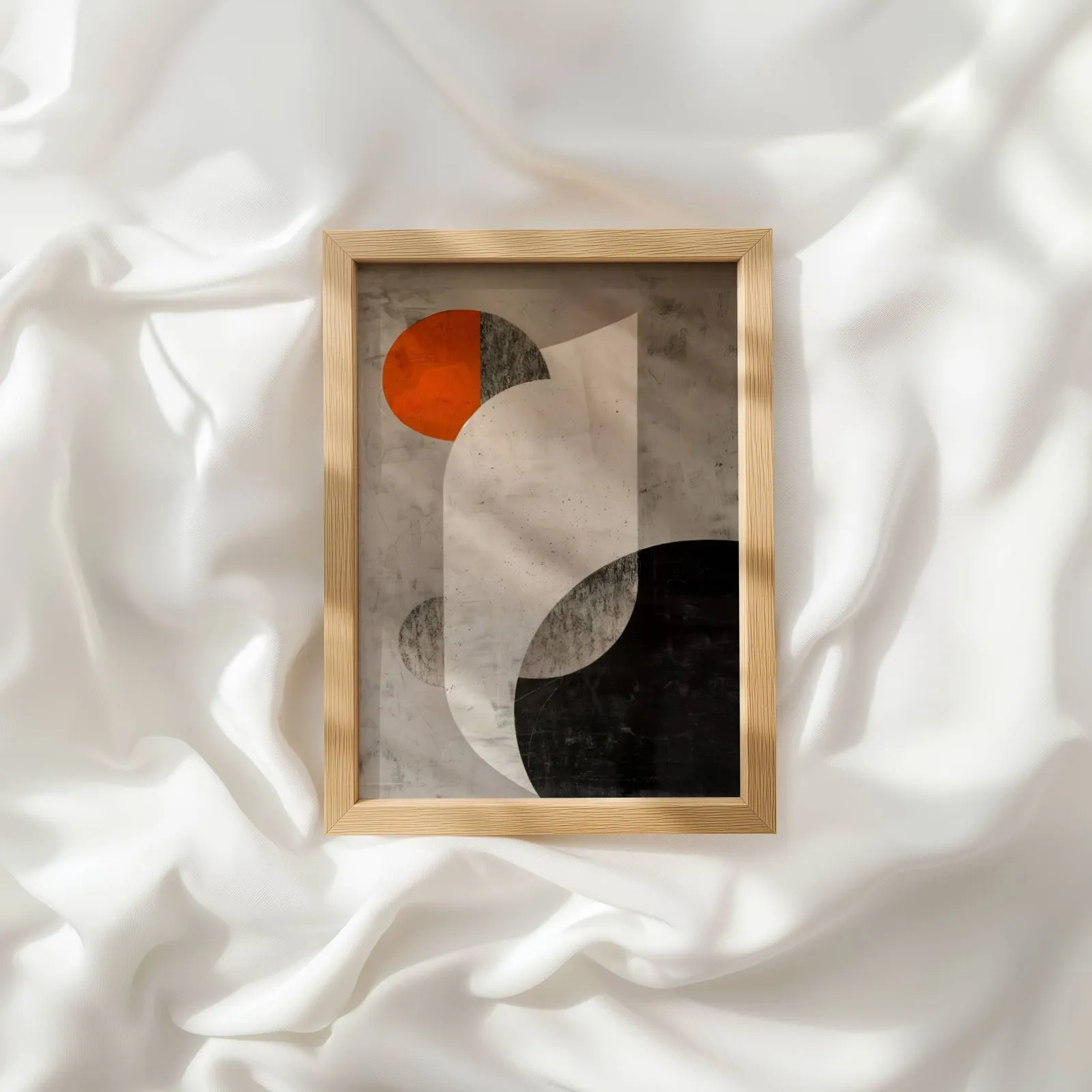 orange and black abstract geometric wall art, resting atop rumpled white silky fabric