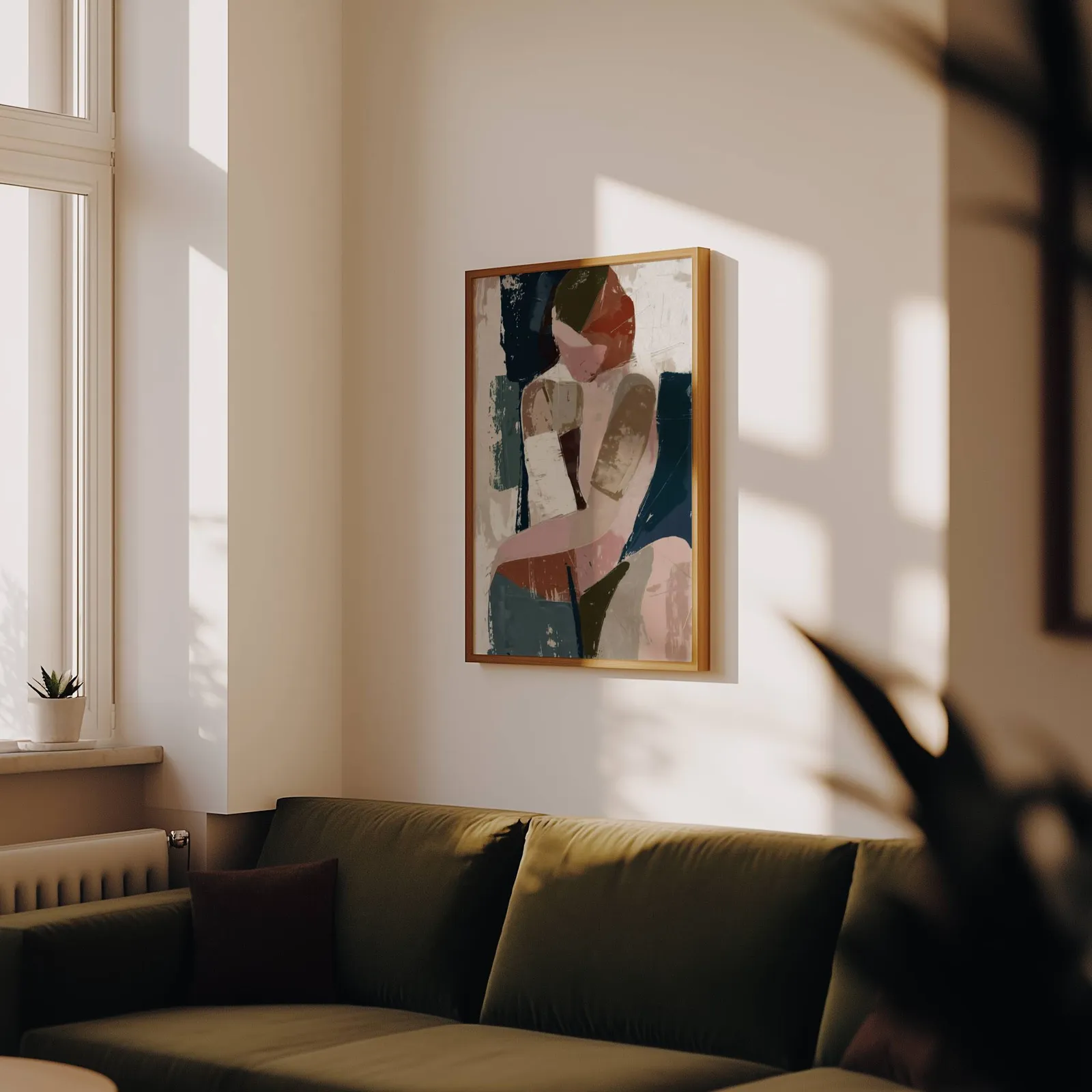 abstract face art in terracotta pink and navy, above an olive velvet sofa in raking afternoon light