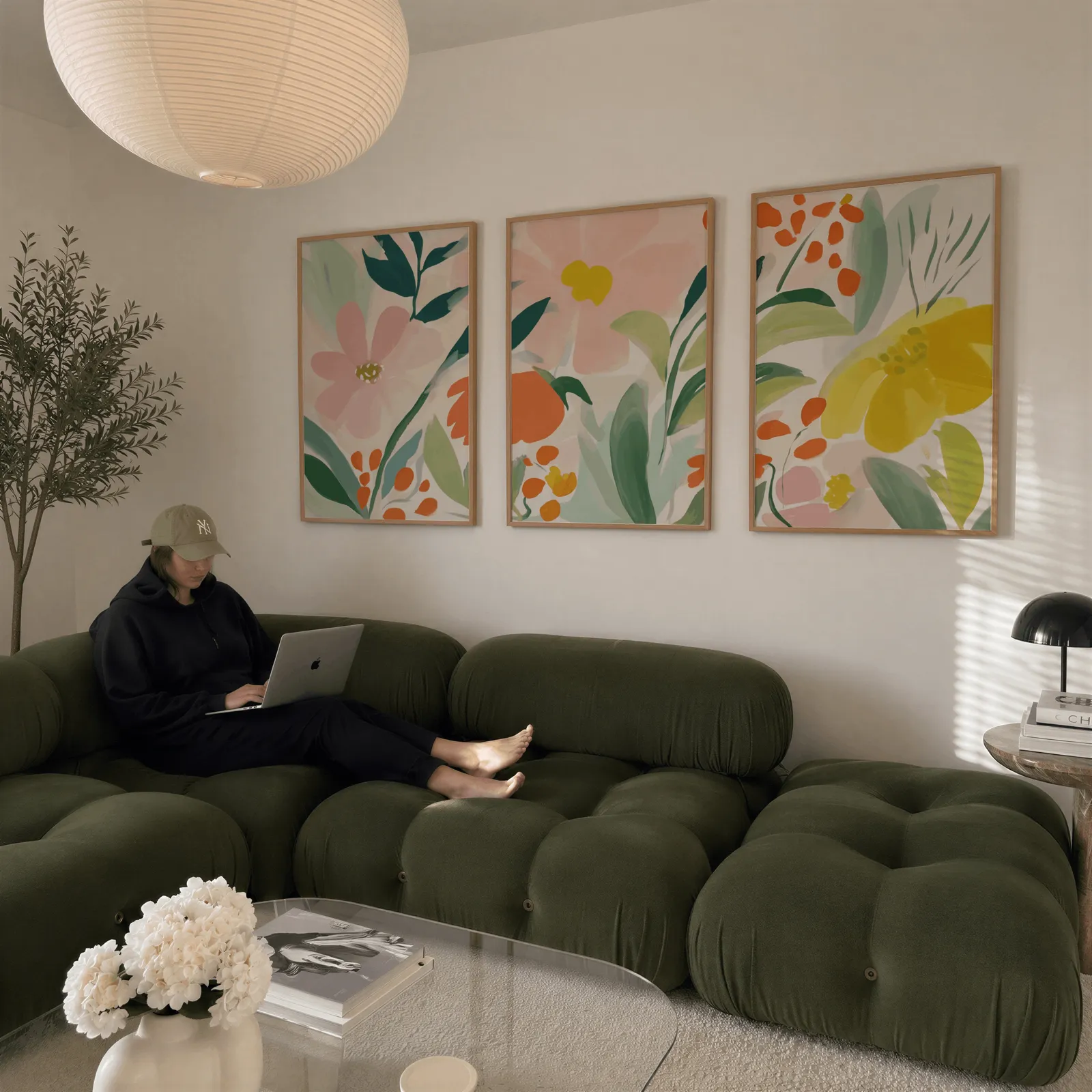 colorful floral botanical wall art set of 3, above a plush olive velvet sectional beneath a paper lantern light