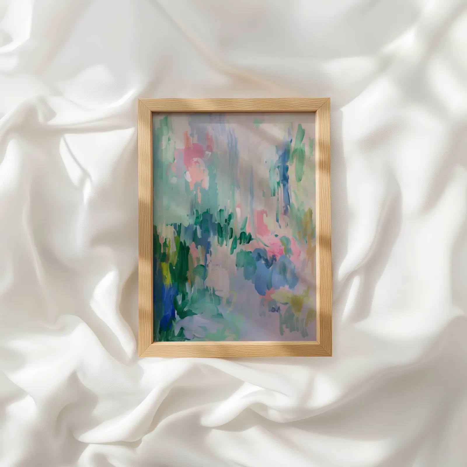 colorful abstract floral wall art in green and pink, resting atop rumpled white silky fabric