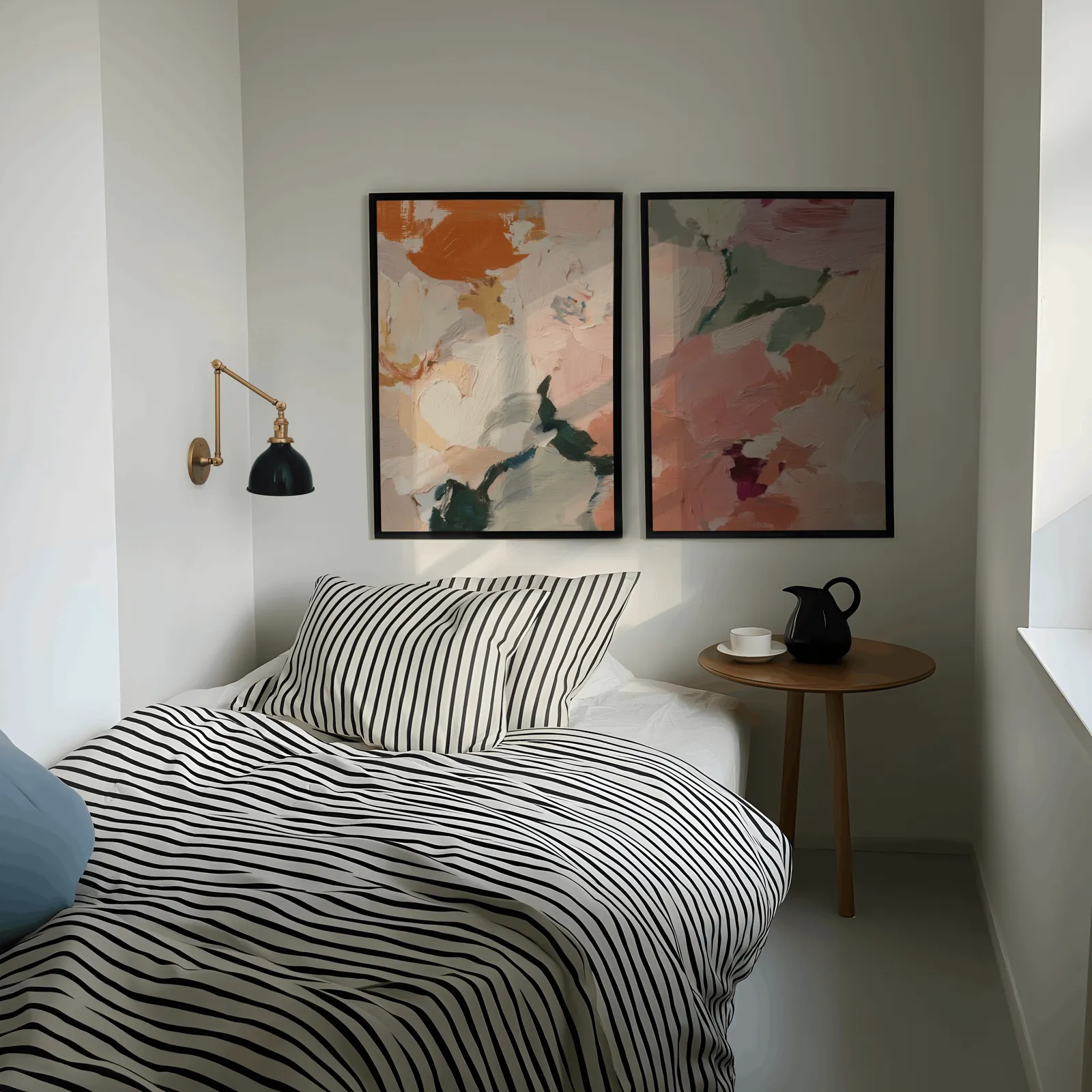 pink and green abstract floral wall art set of two, above a striped bed beside a brass swing-arm lamp