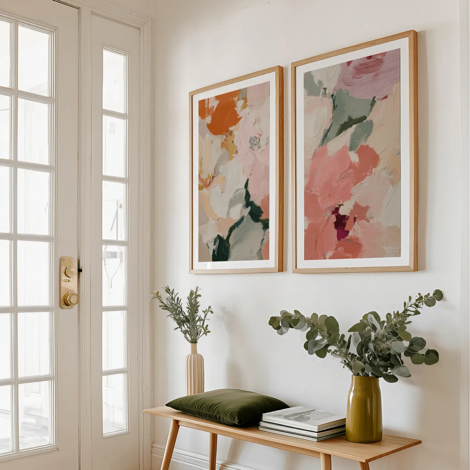 pink and green abstract floral wall art set of two, above a wooden bench with eucalyptus stems and a green cushion