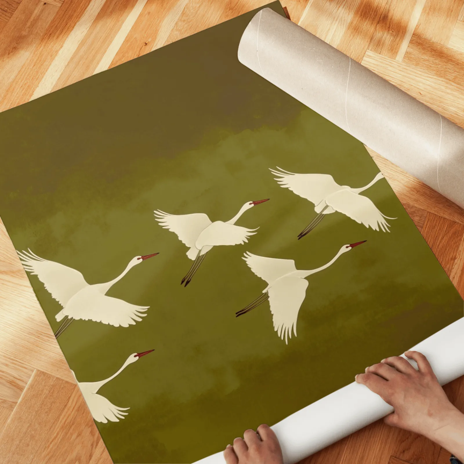 green cranes triptych wall art, unrolled across a herringbone wood floor by hand