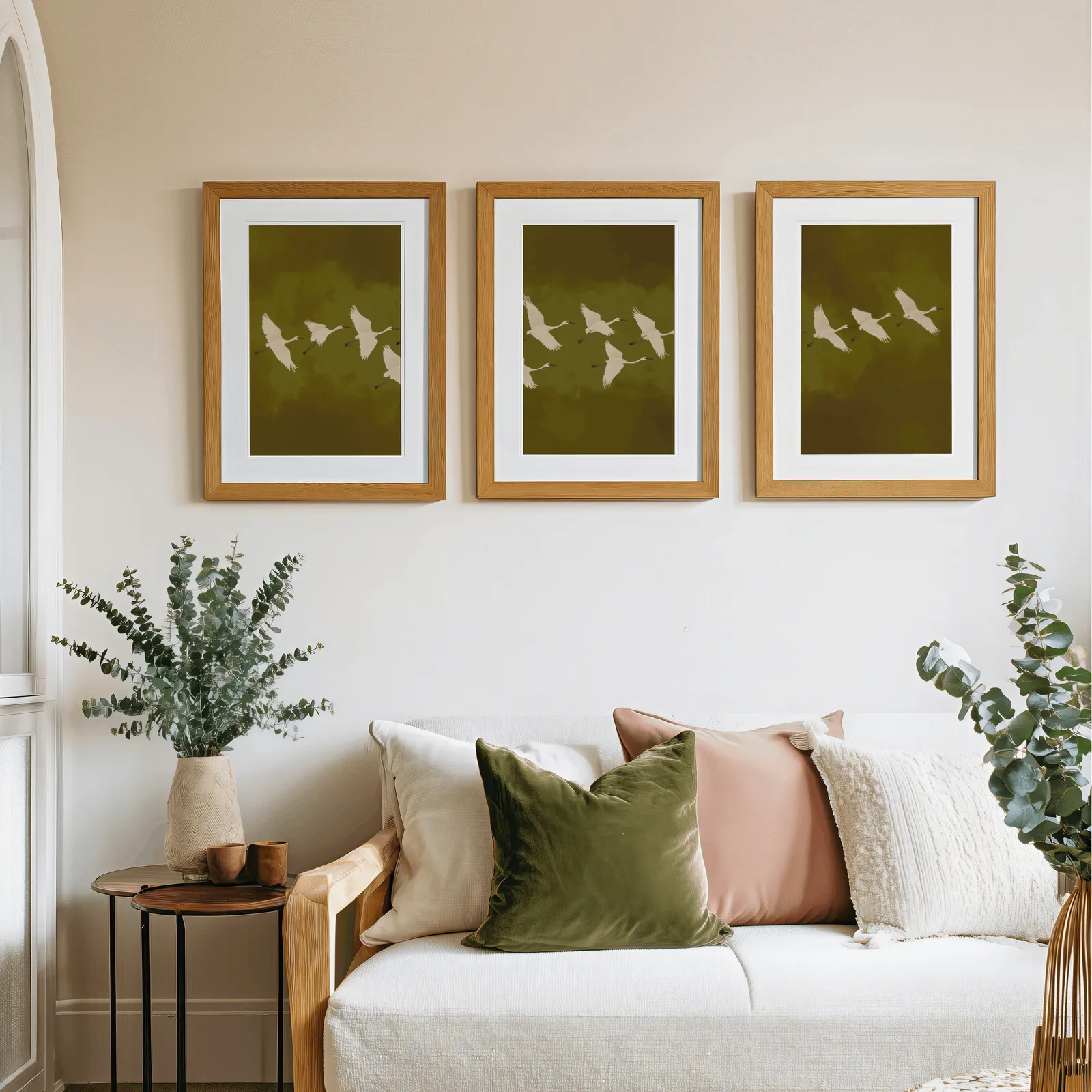 green cranes triptych wall art, above a cream sofa piled with olive and blush pillows