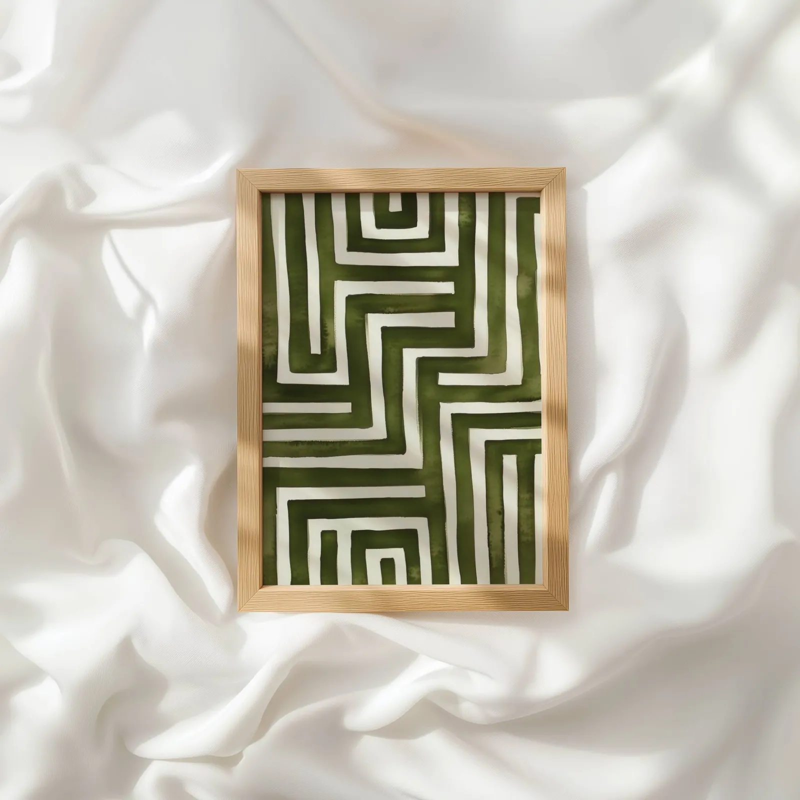 green abstract maze minimalist wall art, resting atop rumpled white silky fabric