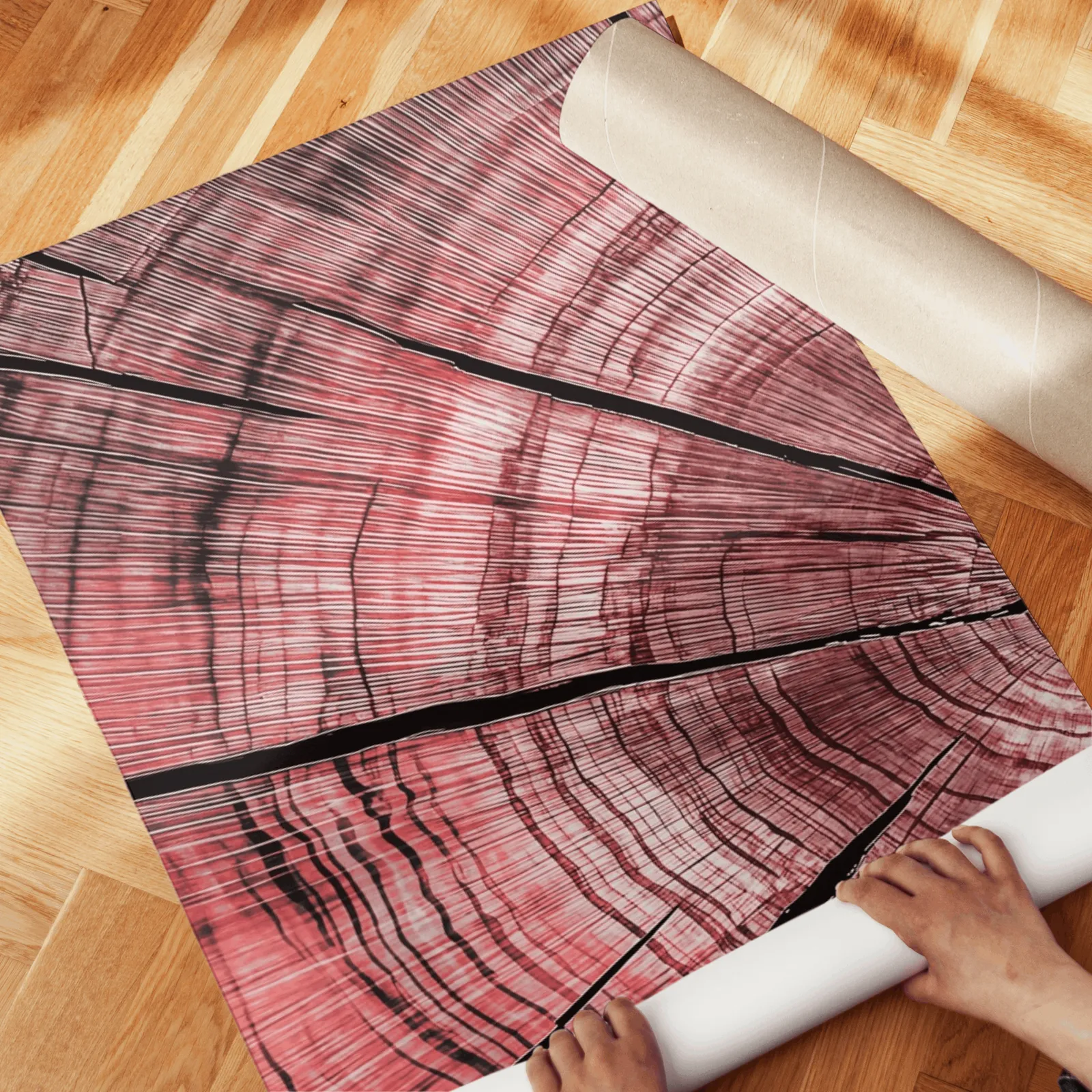 pink tree rings triptych wall art, unrolled across a herringbone wood floor by hand