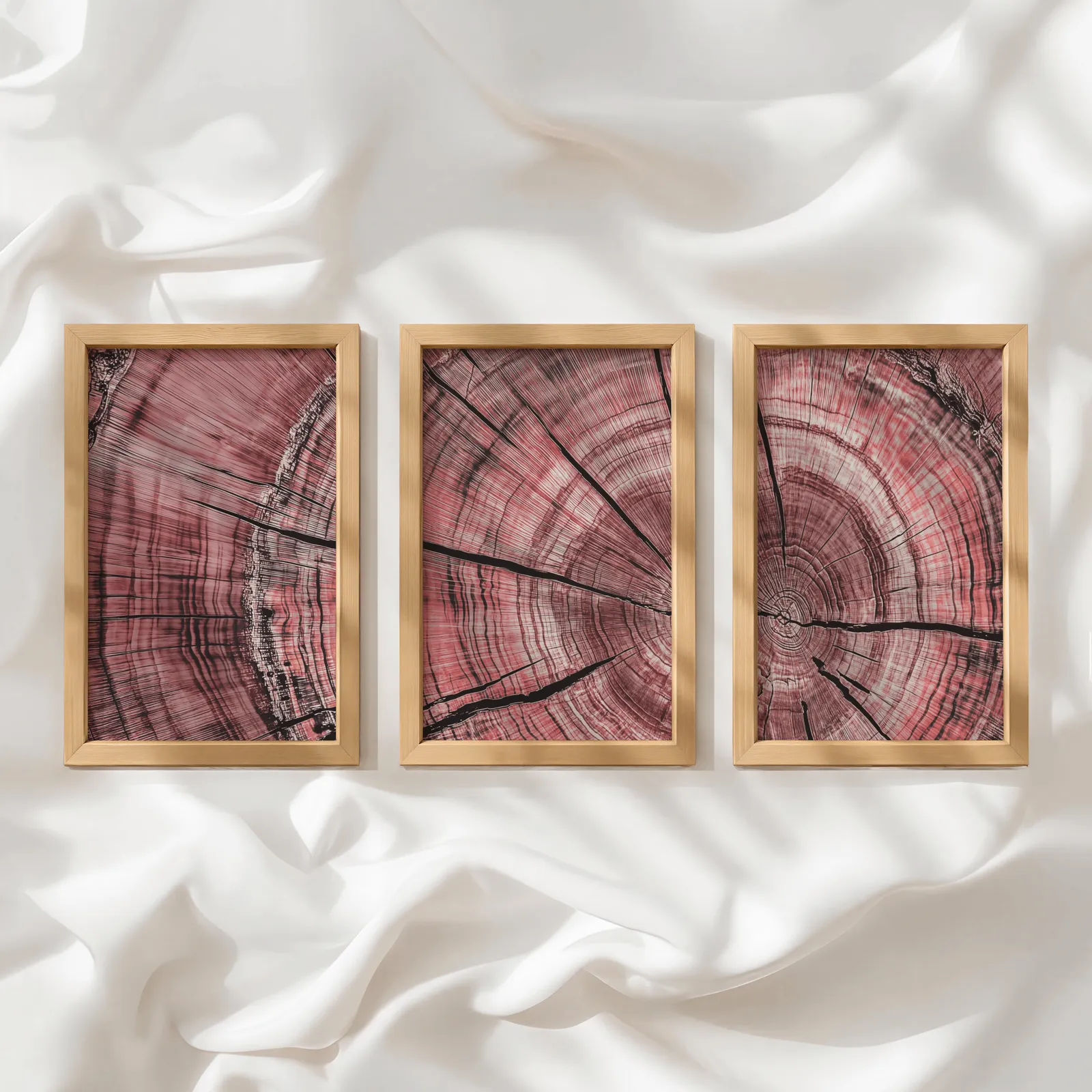 pink tree rings triptych wall art, in a row atop rumpled white silky fabric