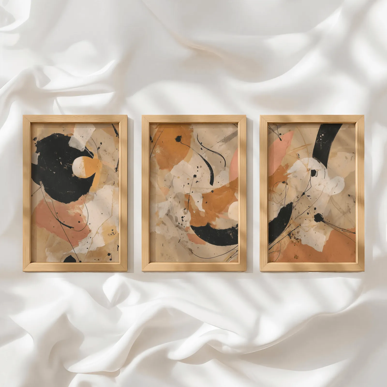 terracotta black abstract three piece wall art, in a row atop rumpled white silky fabric