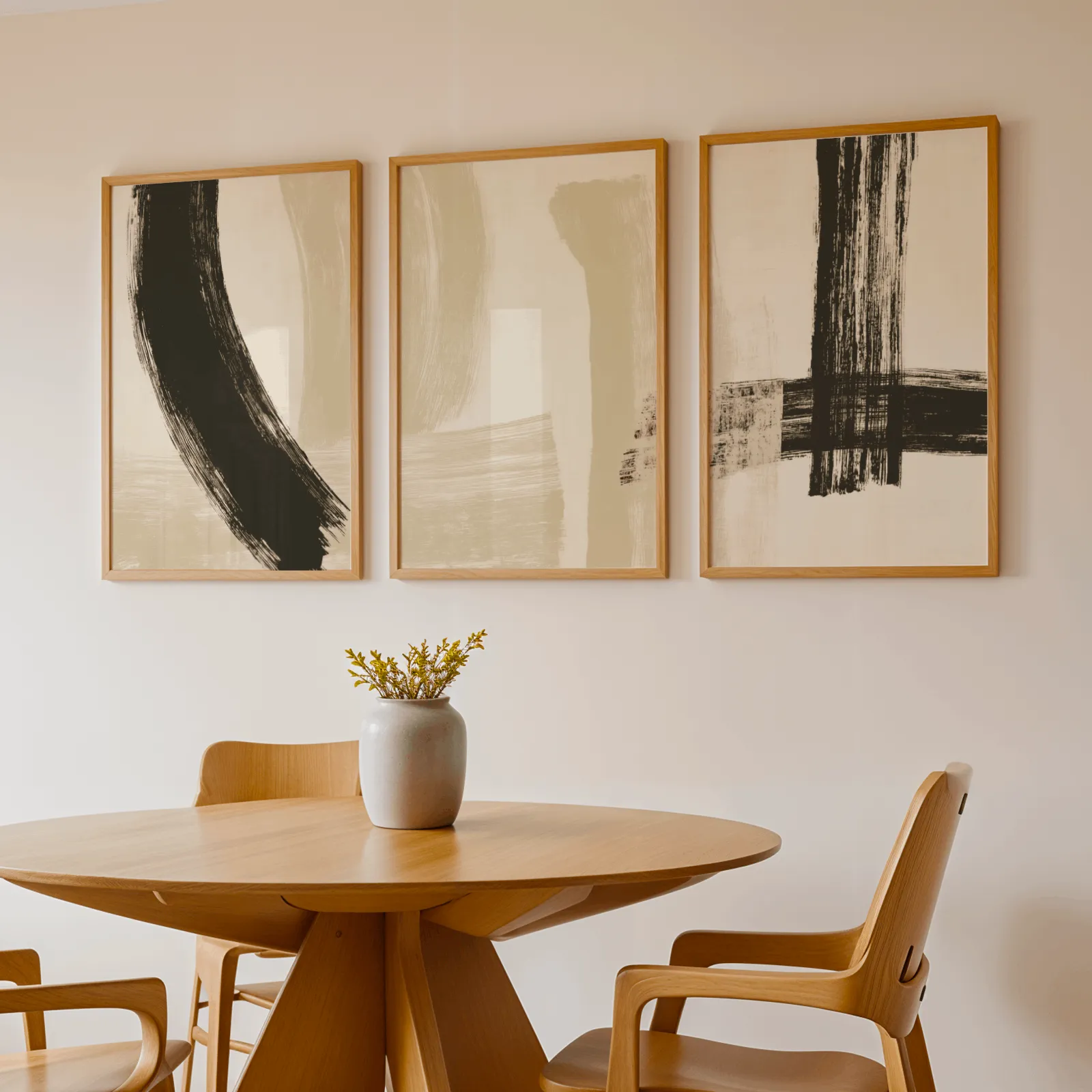 black and beige abstract minimalist triptych wall art, above a round wooden table with a stoneware vase