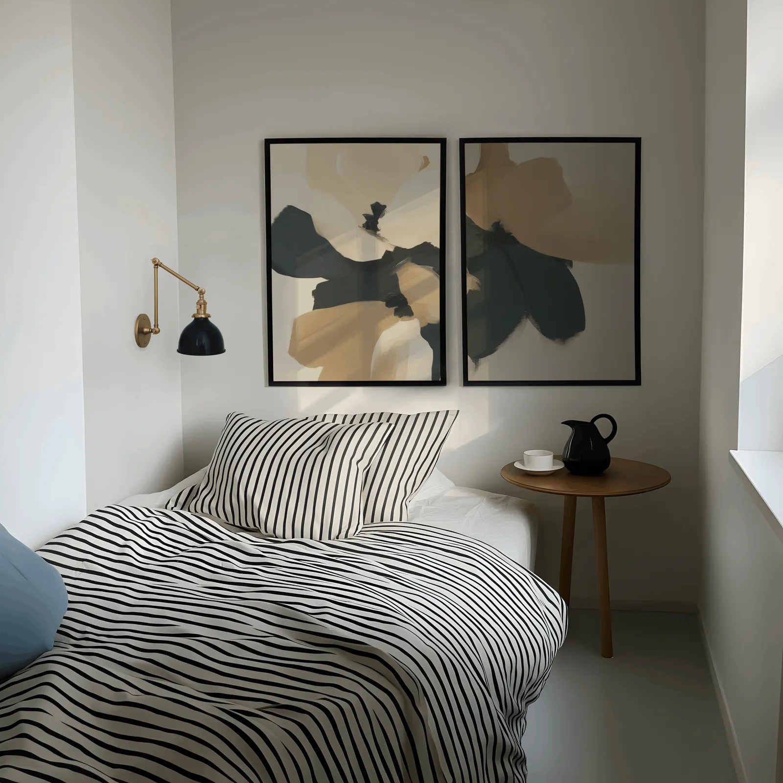 beige and black abstract floral wall art set of 2, above a striped bed beside a brass swing-arm lamp
