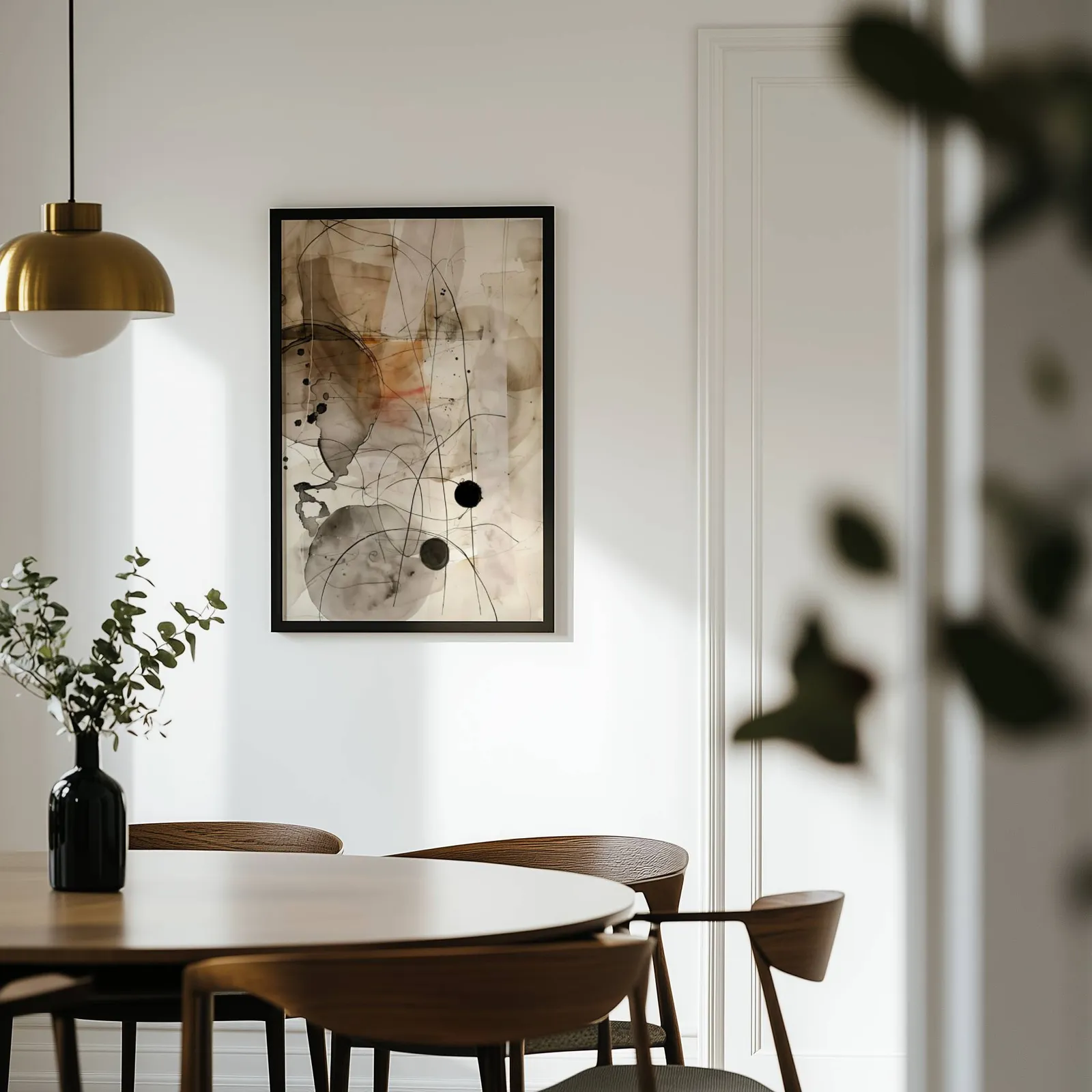 abstract ink wall art in beige and black, on a white wall above a round wooden dining table