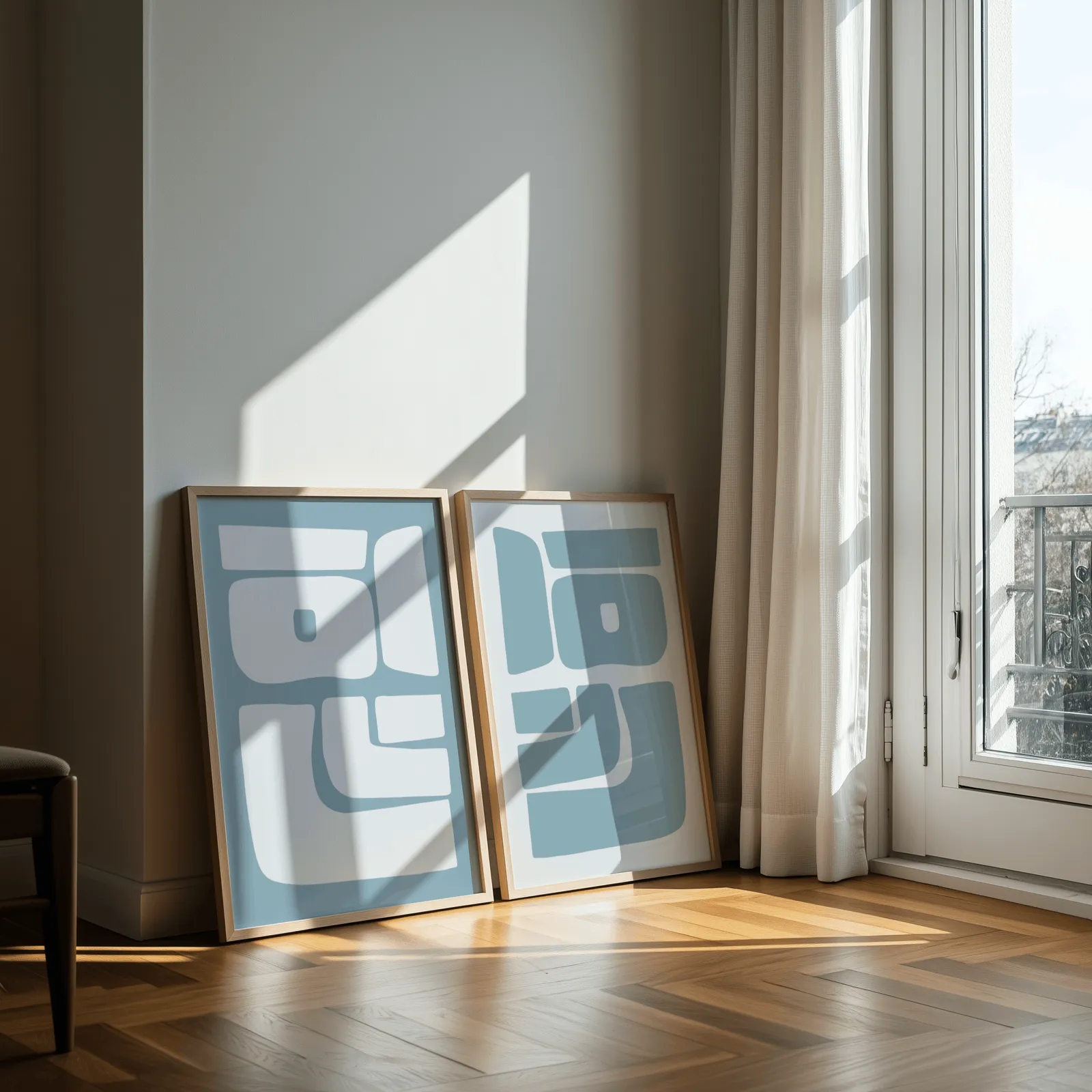 blue abstract minimalist wall art set of 2, leaning against a sunlit wall by a curtained balcony door