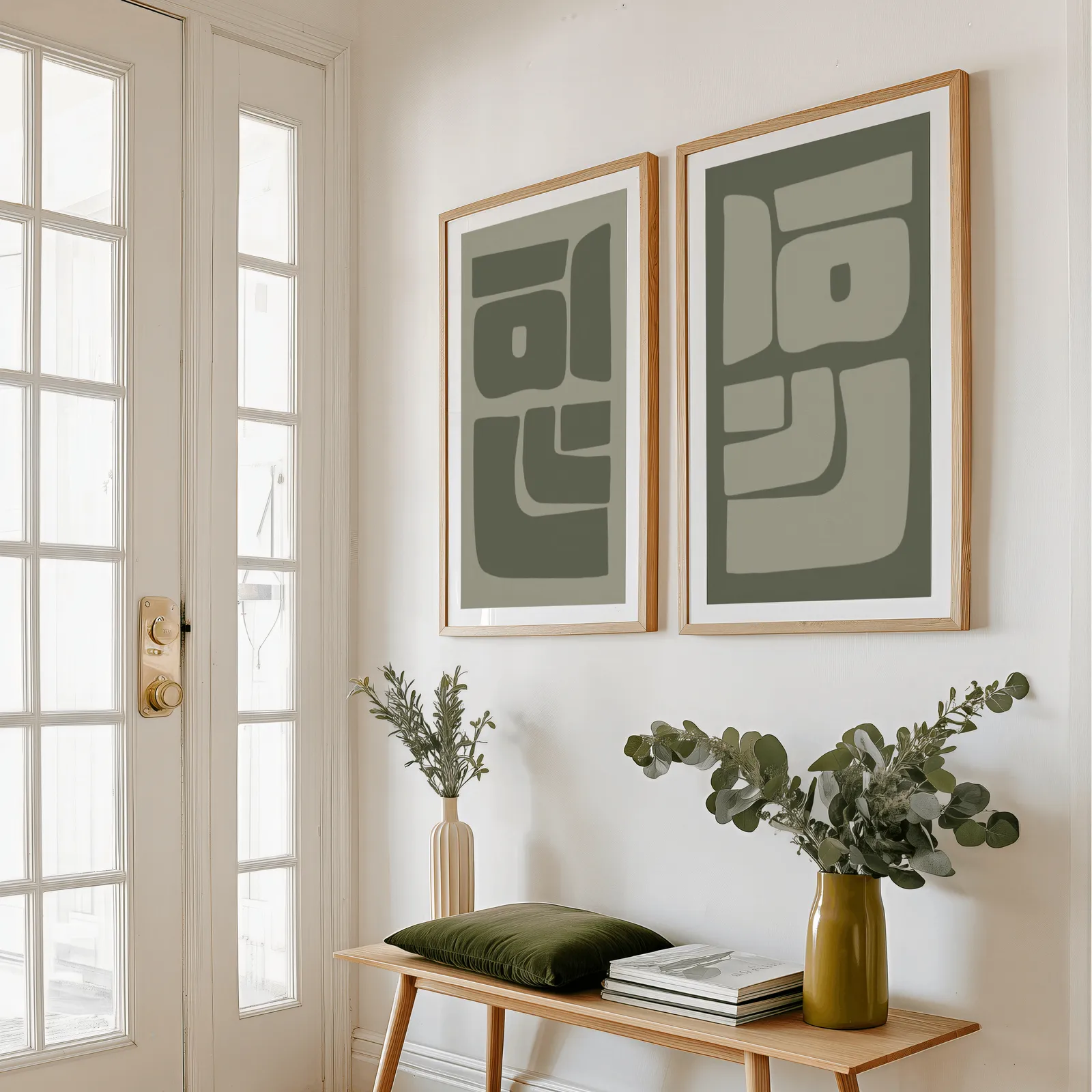 green abstract minimalist wall art set of two, above a wooden bench with eucalyptus stems and a green cushion