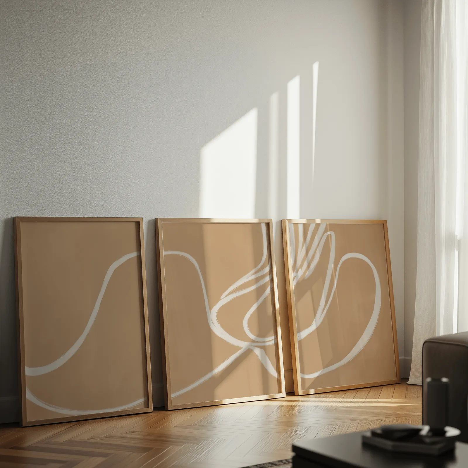 beige abstract minimalist wall art set of three, leaning against a sunlit wall on herringbone flooring