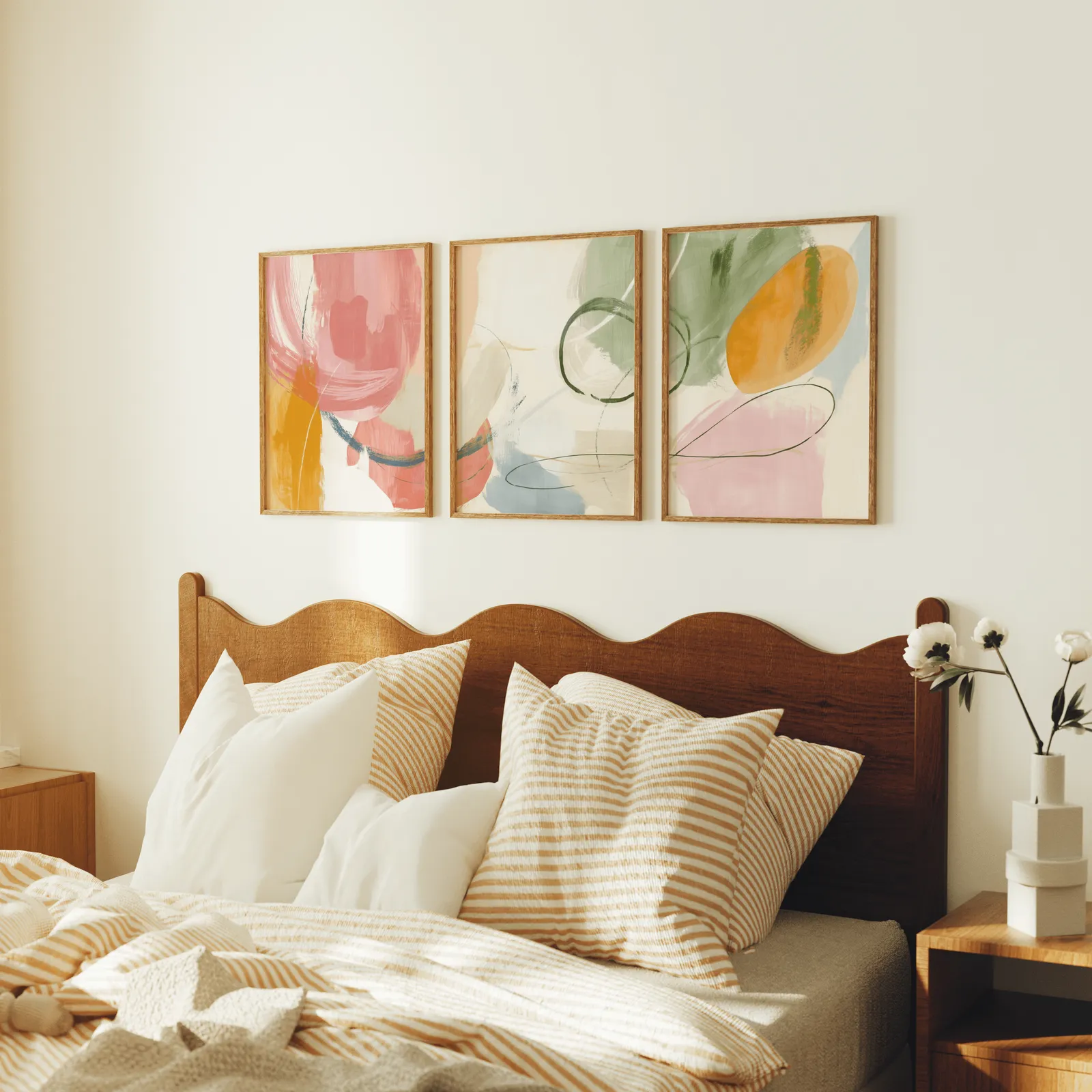 colorful abstract wall art set of 3, above a scalloped wooden headboard with striped pillows