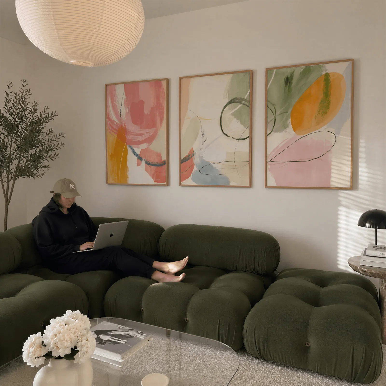 colorful abstract wall art set of 3, above a plush olive velvet sectional beneath a paper lantern light