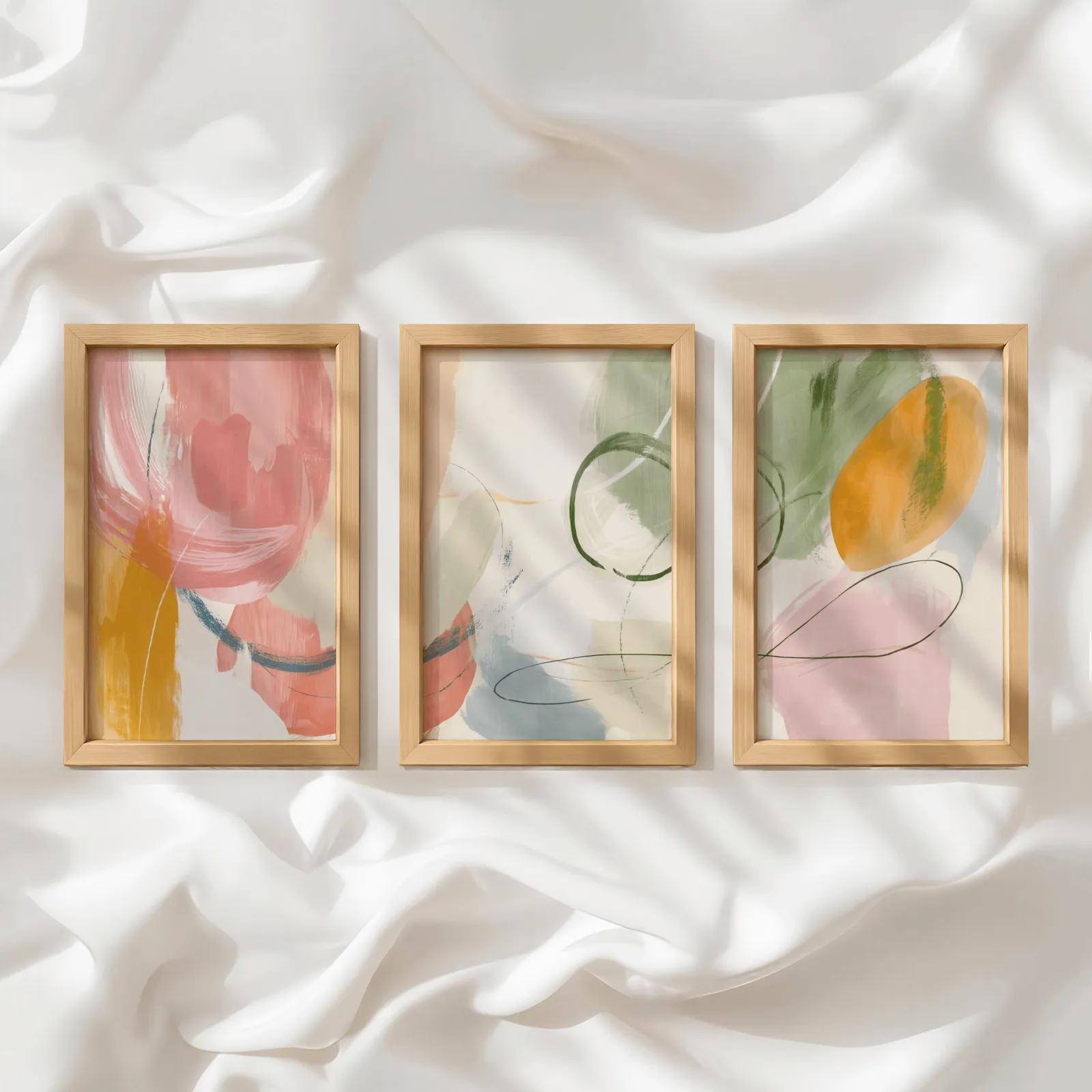 colorful abstract wall art set of 3, in a row atop rumpled white silky fabric
