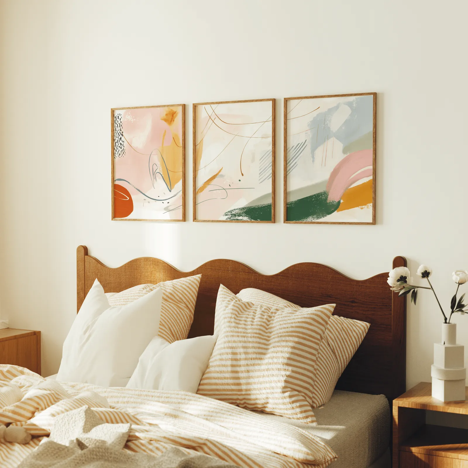 colorful abstract wall art set of three, above a scalloped wooden headboard with striped pillows
