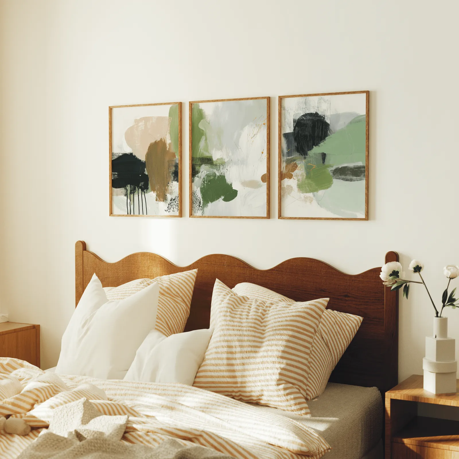 green and blush abstract wall art set of 3, above a scalloped wooden headboard with striped pillows