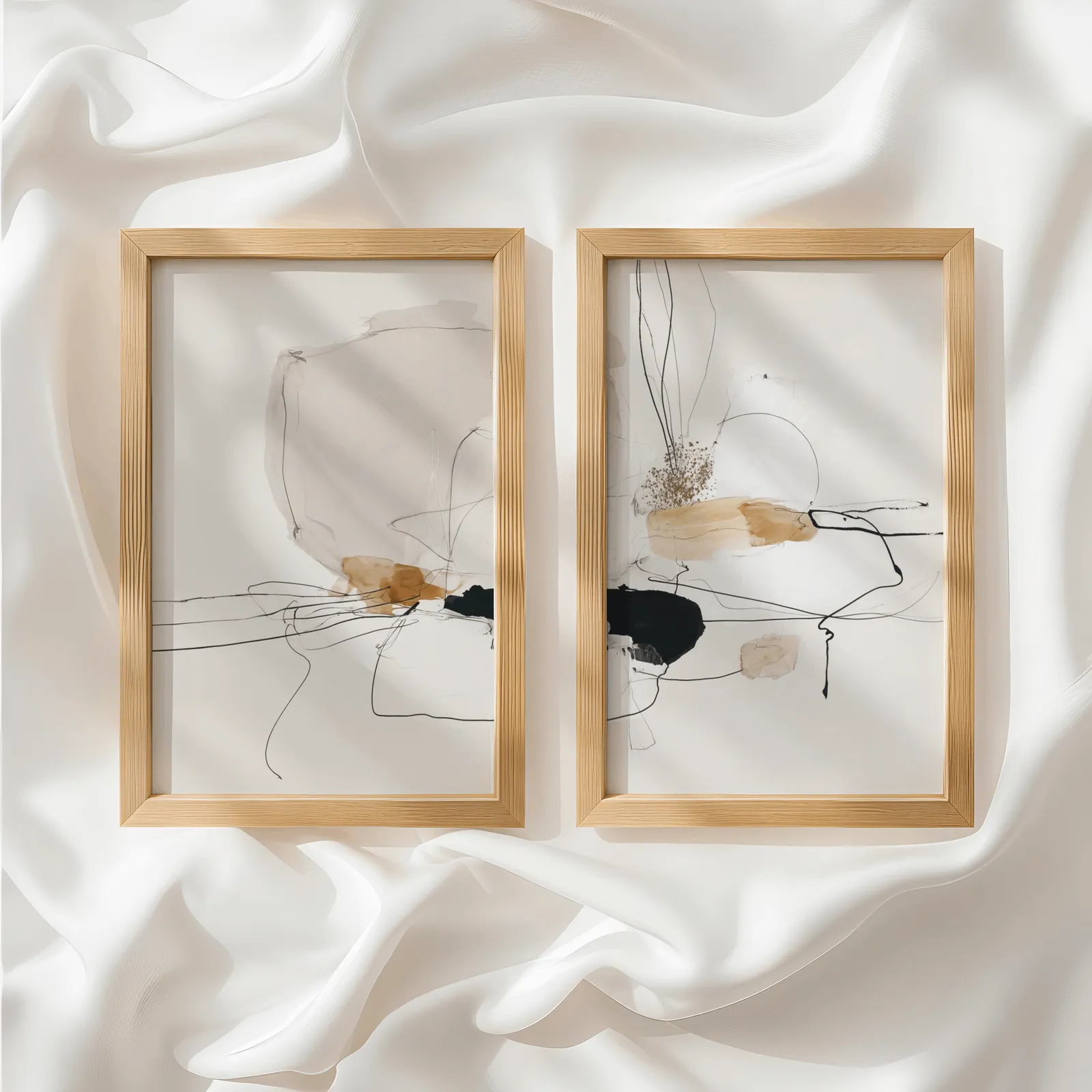 beige abstract minimalist wall art set of two, side by side atop rumpled white silky fabric