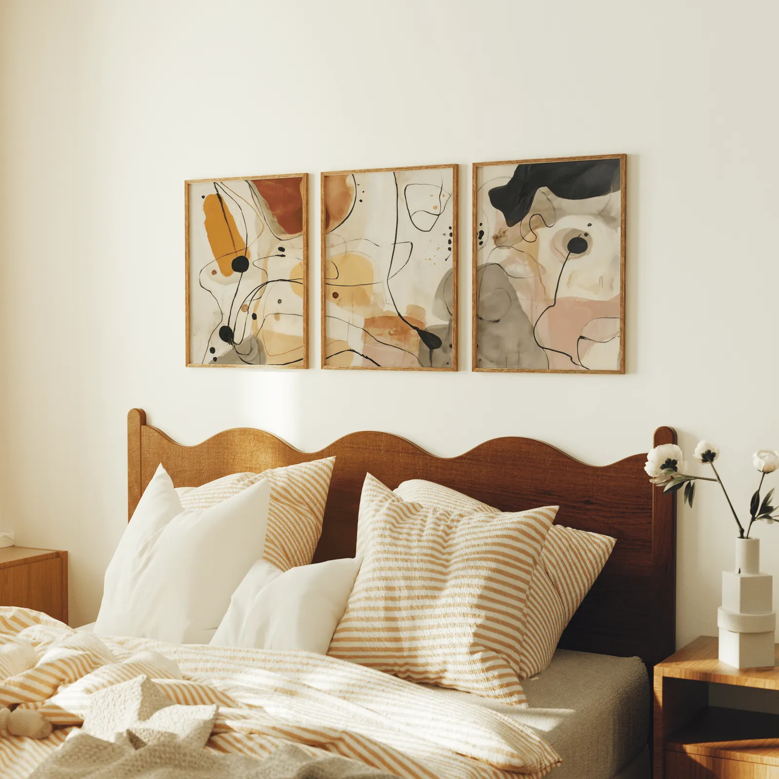 terracotta abstract line art set of three, above a scalloped wooden headboard with striped pillows