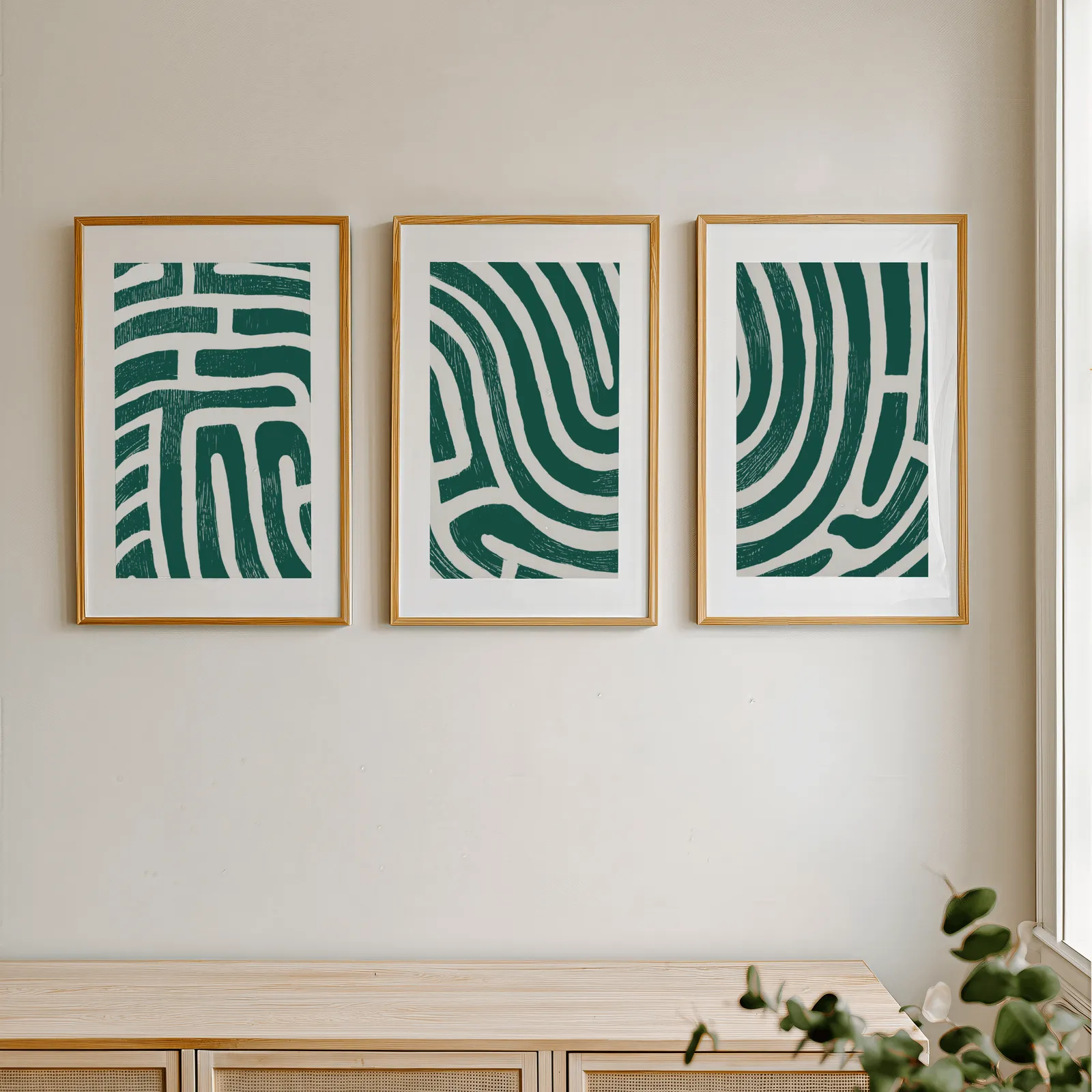 green abstract maze line triptych wall art, in a row above a light wooden sideboard near a window