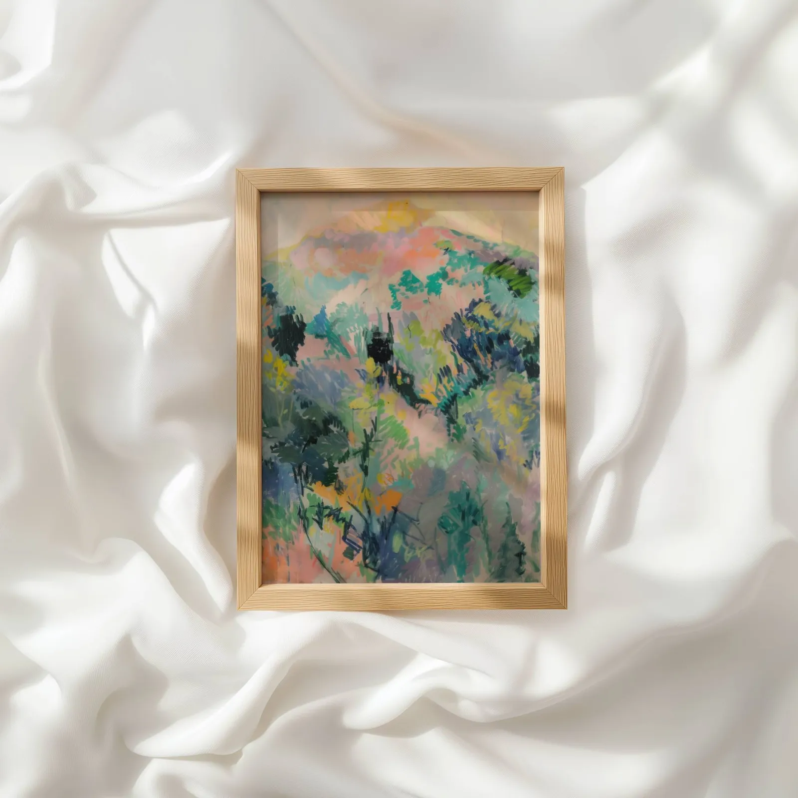 colorful landscape wall art of hillside foliage, resting atop rumpled white silky fabric