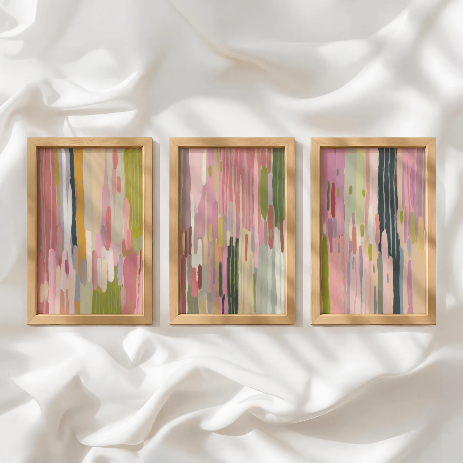 colorful abstract wall art set of 3, in a row atop rumpled white silky fabric