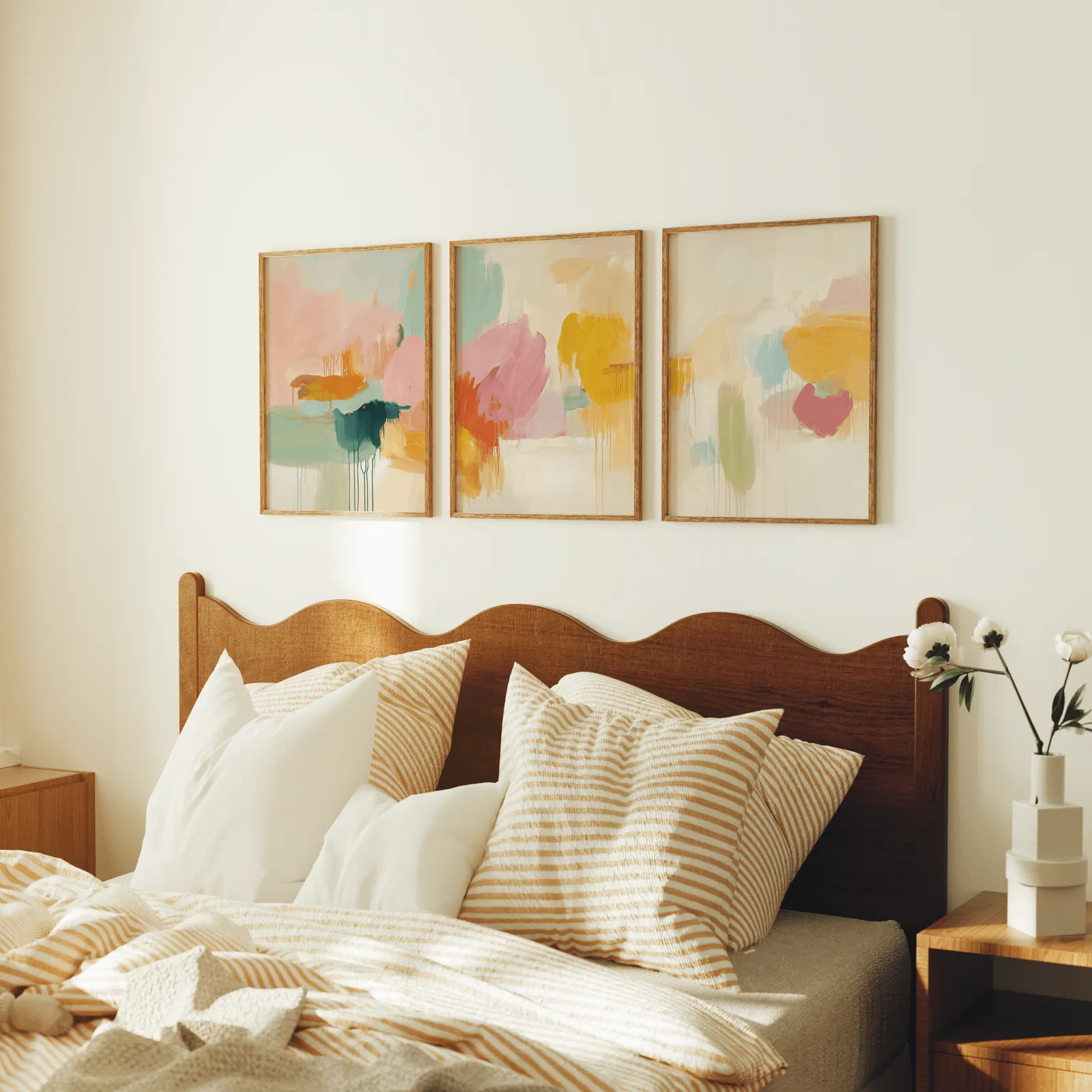 colorful abstract wall art set of 3, above a scalloped wooden headboard with striped pillows