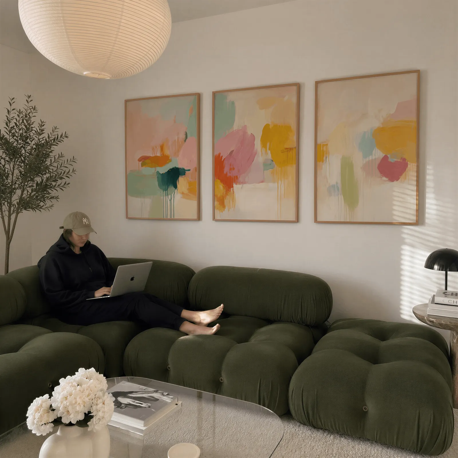 colorful abstract wall art set of 3, above a plush olive velvet sectional beneath a paper lantern light